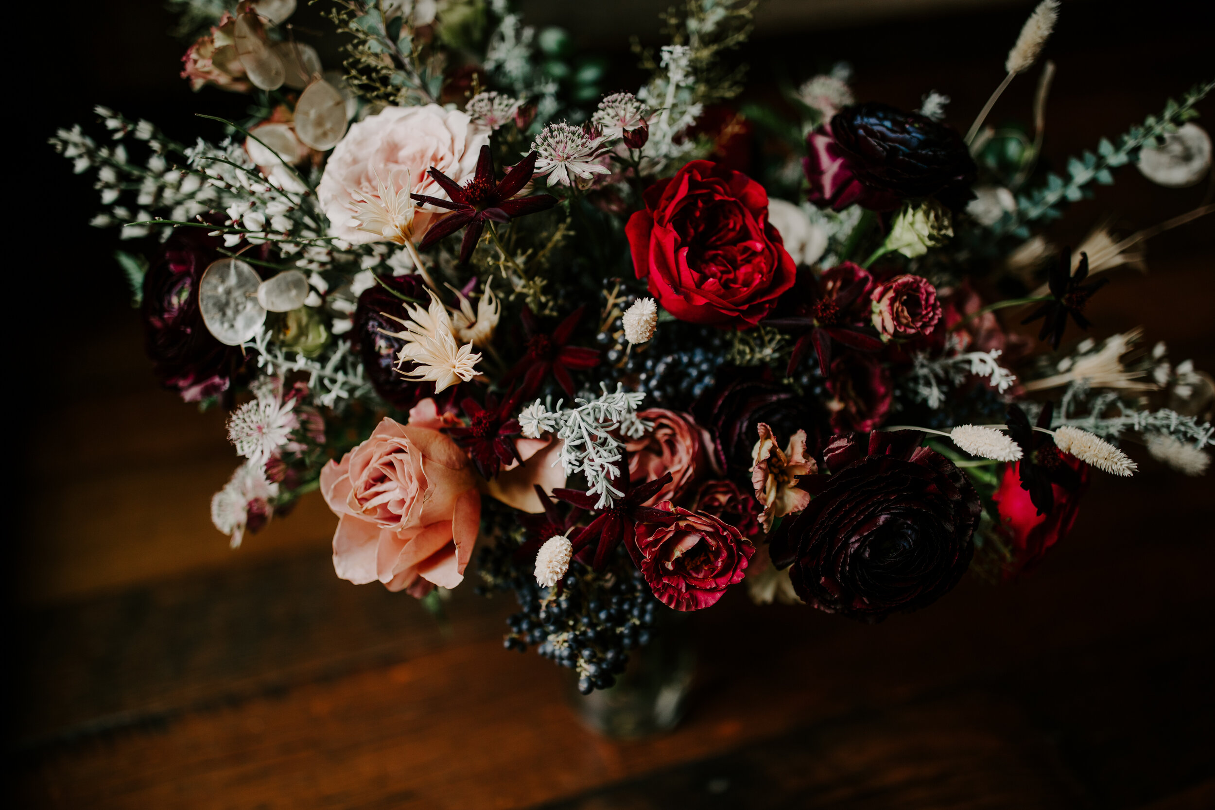 Loose, whimsical winter bridal bouquet with eggplant, blush, mauve, and burgundy garden roses and ranunculus, dried flowers, and natural, untamed greenery. Nashville wedding floral design at the Cordelle.