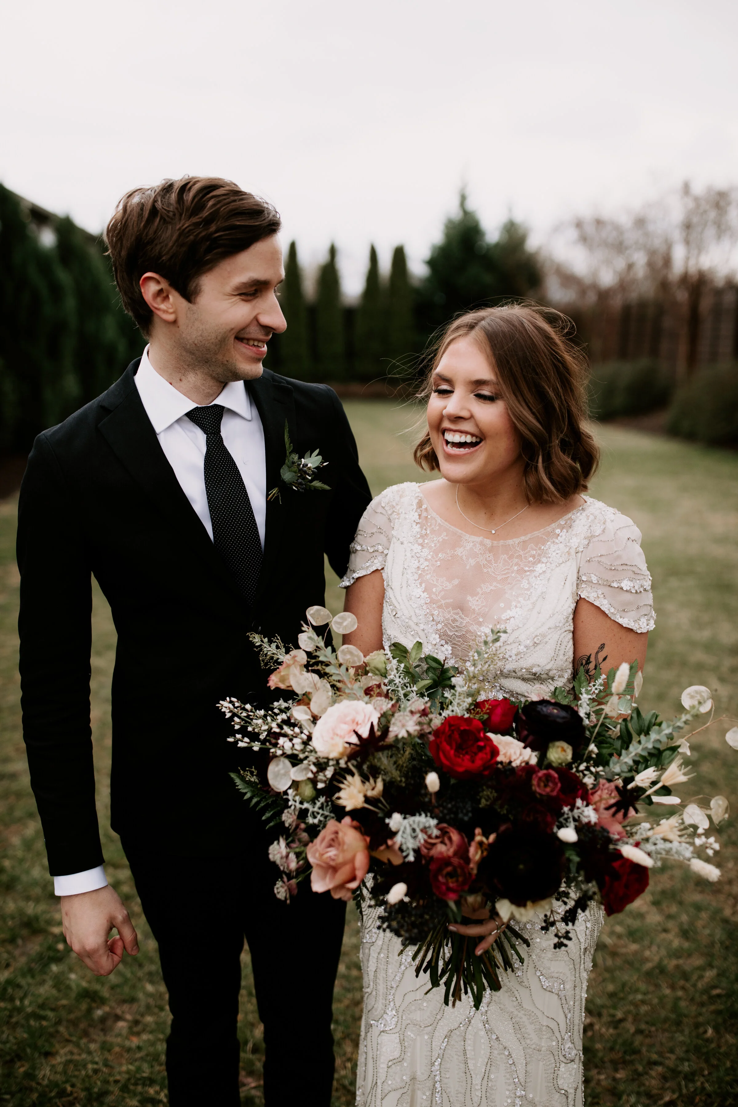 Loose, whimsical winter bridal bouquet with eggplant, blush, mauve, and burgundy garden roses and ranunculus, dried flowers, and natural, untamed greenery. Nashville wedding floral design at the Cordelle.