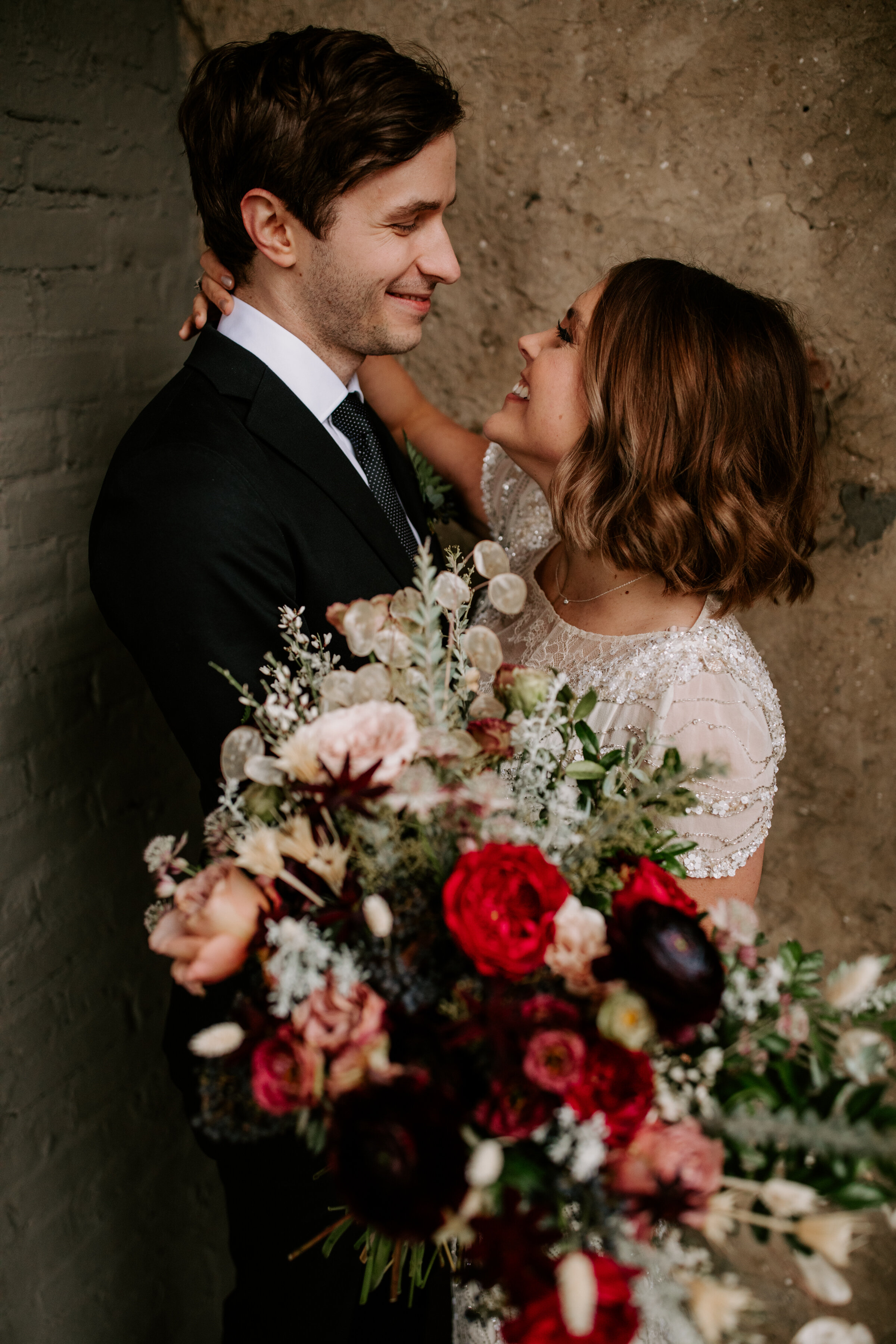 Loose, whimsical winter bridal bouquet with eggplant, blush, mauve, and burgundy garden roses and ranunculus, dried flowers, and natural, untamed greenery. Nashville wedding floral design at the Cordelle.