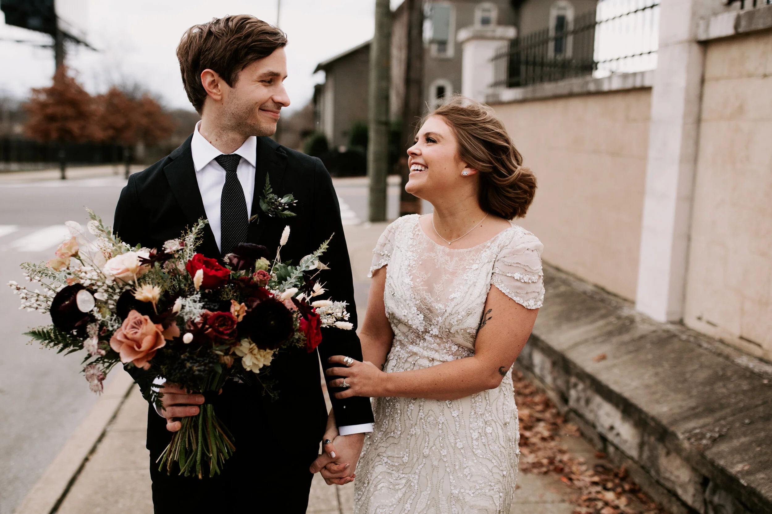 Loose, whimsical winter bridal bouquet with eggplant, blush, mauve, and burgundy garden roses and ranunculus, dried flowers, and natural, untamed greenery. Nashville wedding floral design at the Cordelle.