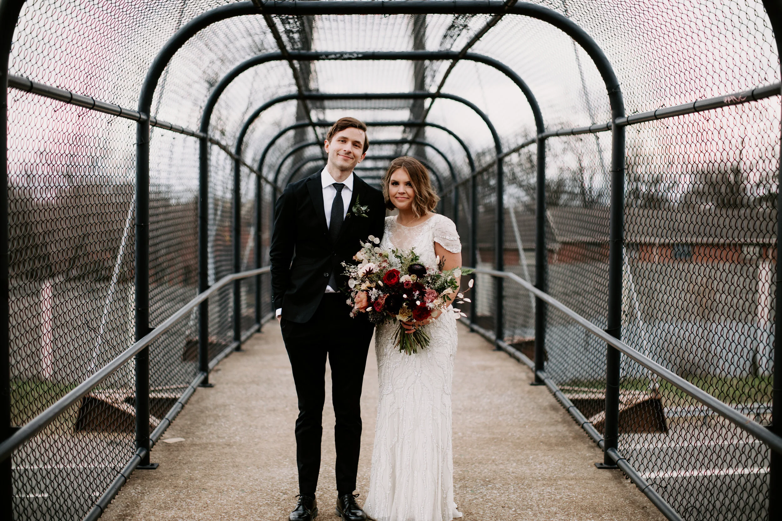 Loose, whimsical winter bridal bouquet with eggplant, blush, mauve, and burgundy garden roses and ranunculus, dried flowers, and natural, untamed greenery. Nashville wedding floral design at the Cordelle.