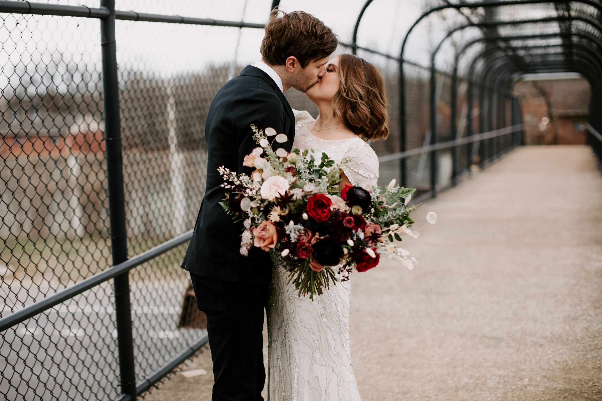 Loose, whimsical winter bridal bouquet with eggplant, blush, mauve, and burgundy garden roses and ranunculus, dried flowers, and natural, untamed greenery. Nashville wedding floral design at the Cordelle.
