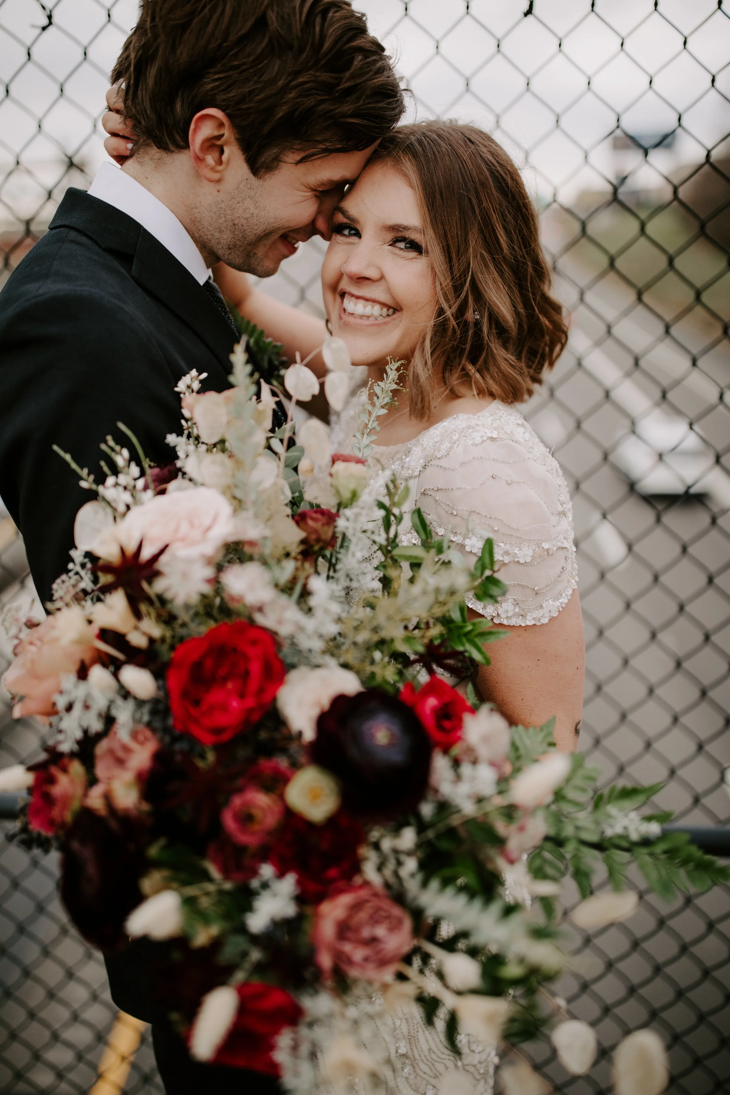 Loose, whimsical winter bridal bouquet with eggplant, blush, mauve, and burgundy garden roses and ranunculus, dried flowers, and natural, untamed greenery. Nashville wedding floral design at the Cordelle.