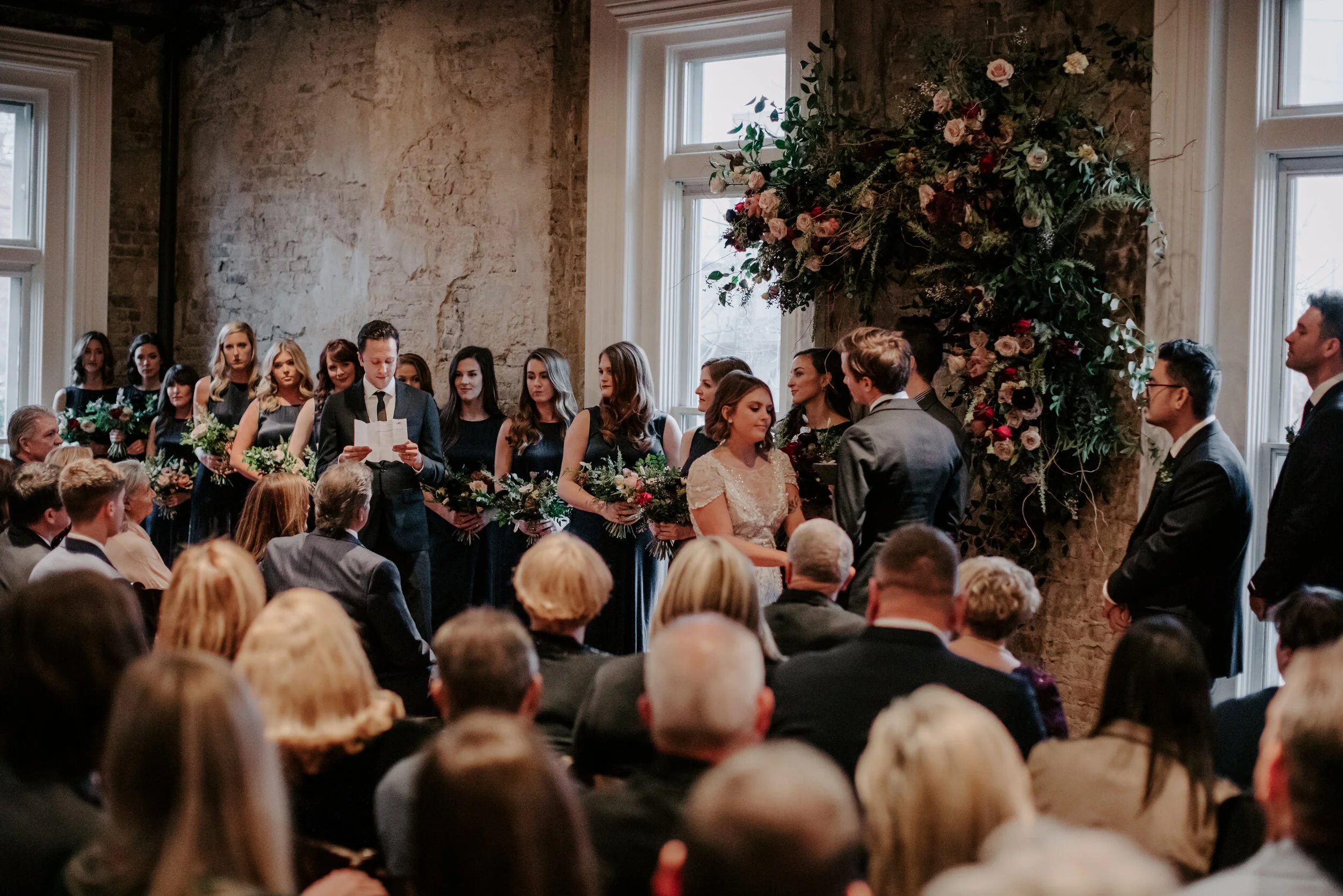 Organic, hanging floral installation for the wedding ceremony backdrop with lush greenery, curly willow branches, and earth toned and burgundy flowers. Nashville wedding florist at the Cordelle.