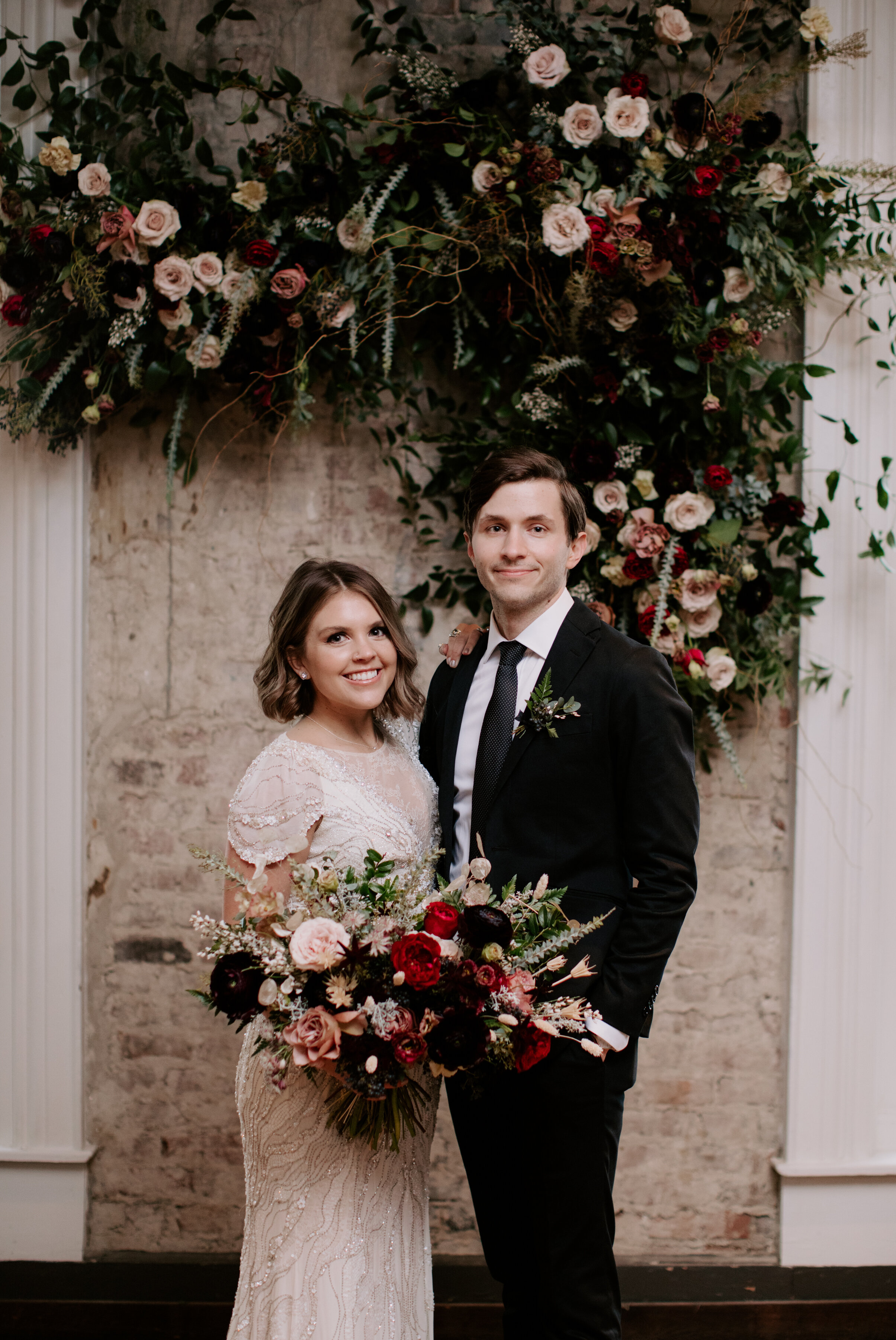 Organic, hanging floral installation for the wedding ceremony backdrop with lush greenery, curly willow branches, and earth toned and burgundy flowers. Nashville wedding florist at the Cordelle.