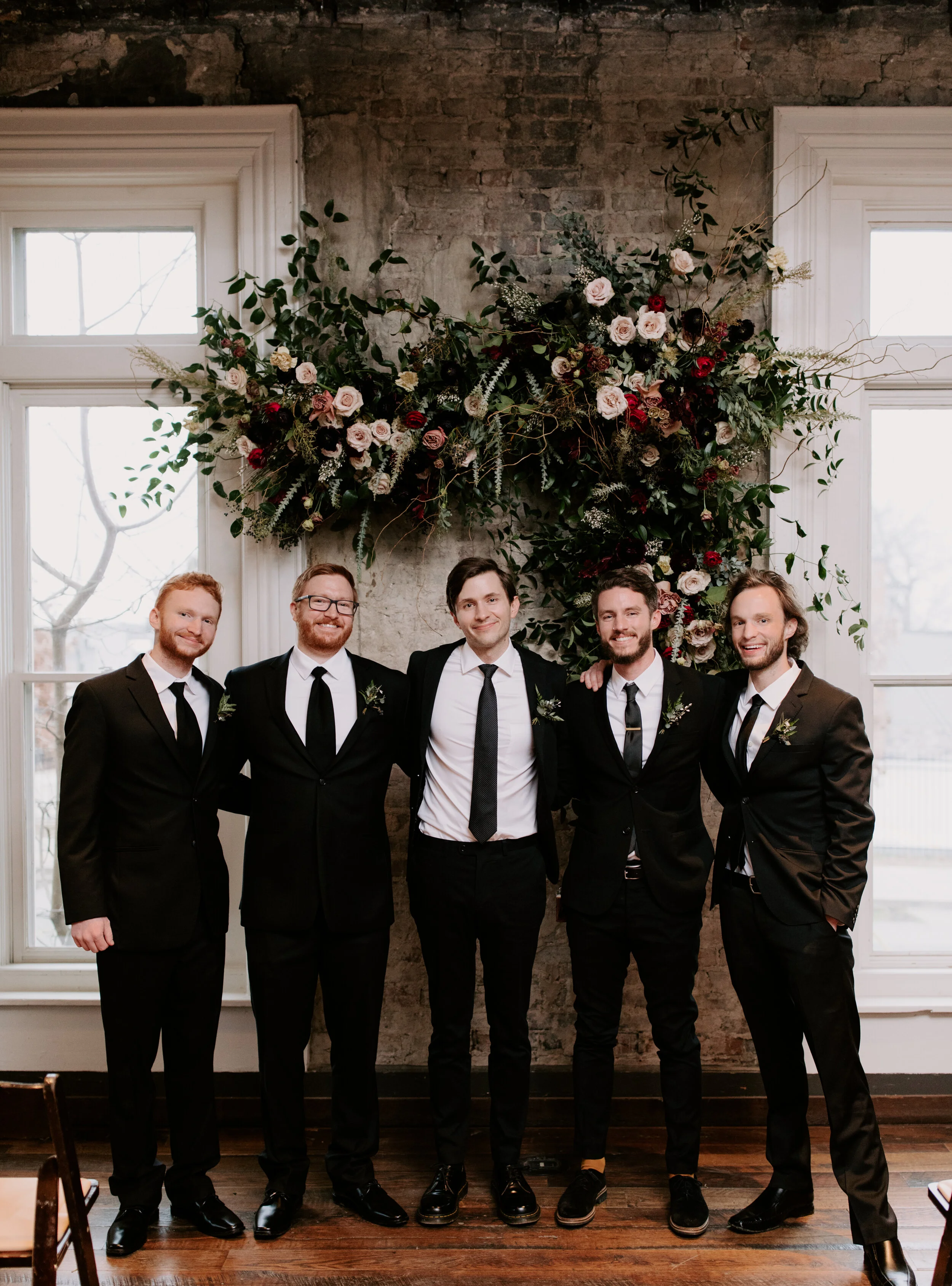 Organic, hanging floral installation for the wedding ceremony backdrop with lush greenery, curly willow branches, and earth toned and burgundy flowers. Nashville wedding florist at the Cordelle.