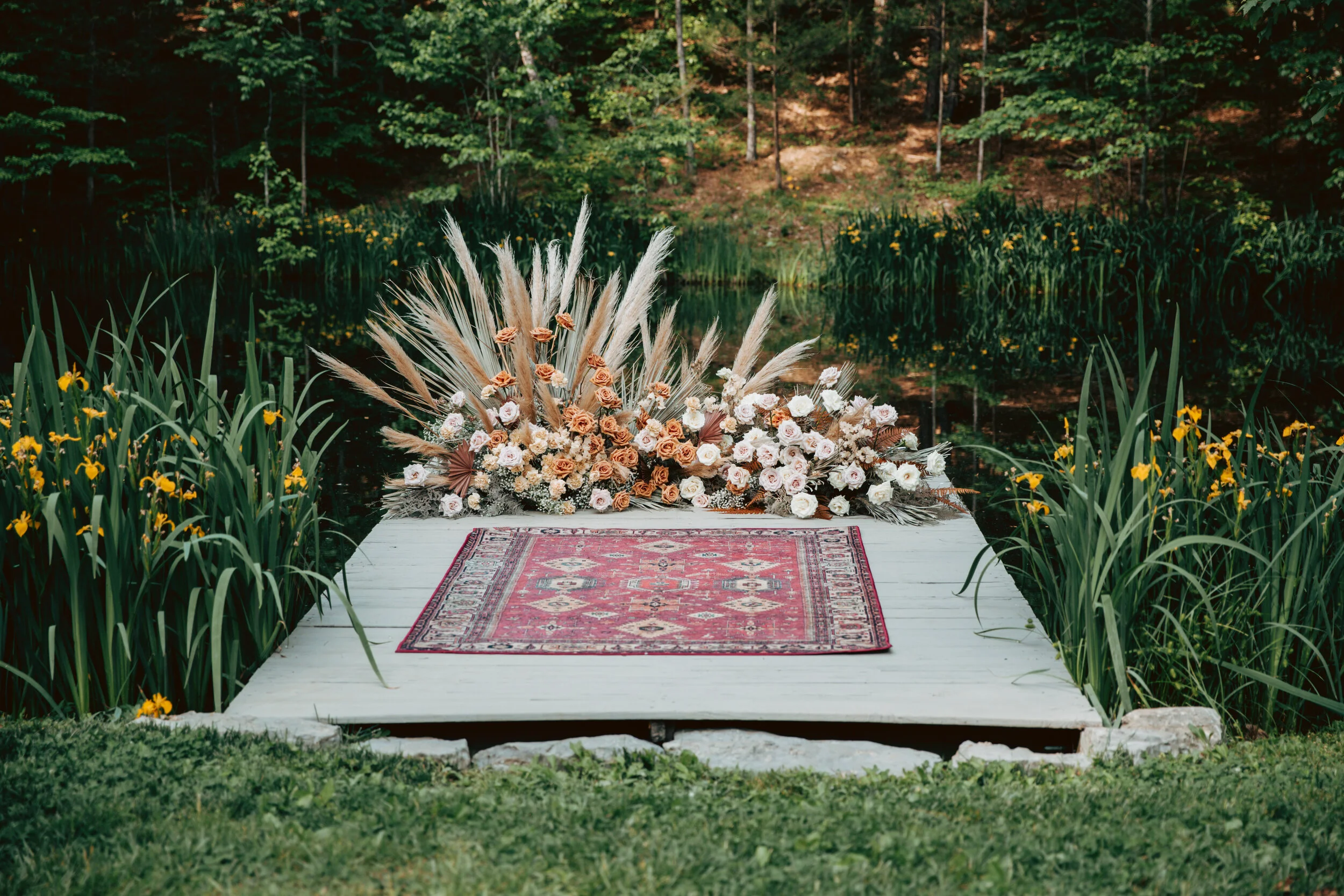 Bohemian, modern floral installation with gold and blush roses, pampas grass, dried ferns, and dried palms, growing on a private dock with a Turkish rug. Nashville wedding florist.