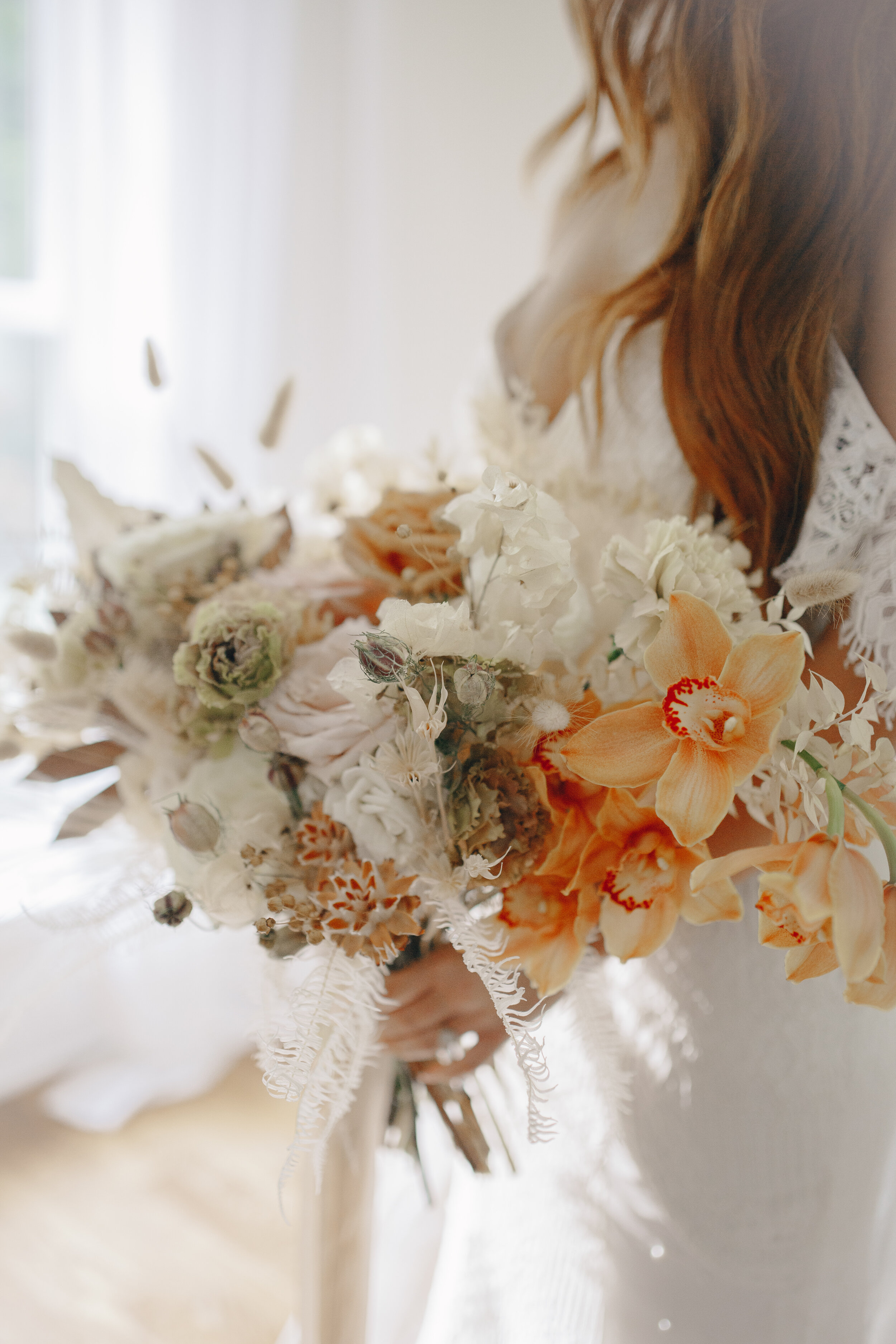 Lush, bohemian bridal bouquet with white garden roses, copper orchids, dried white ferns, earthy textures, and toffee lisianthus. Nashville wedding and elopement floral designer.