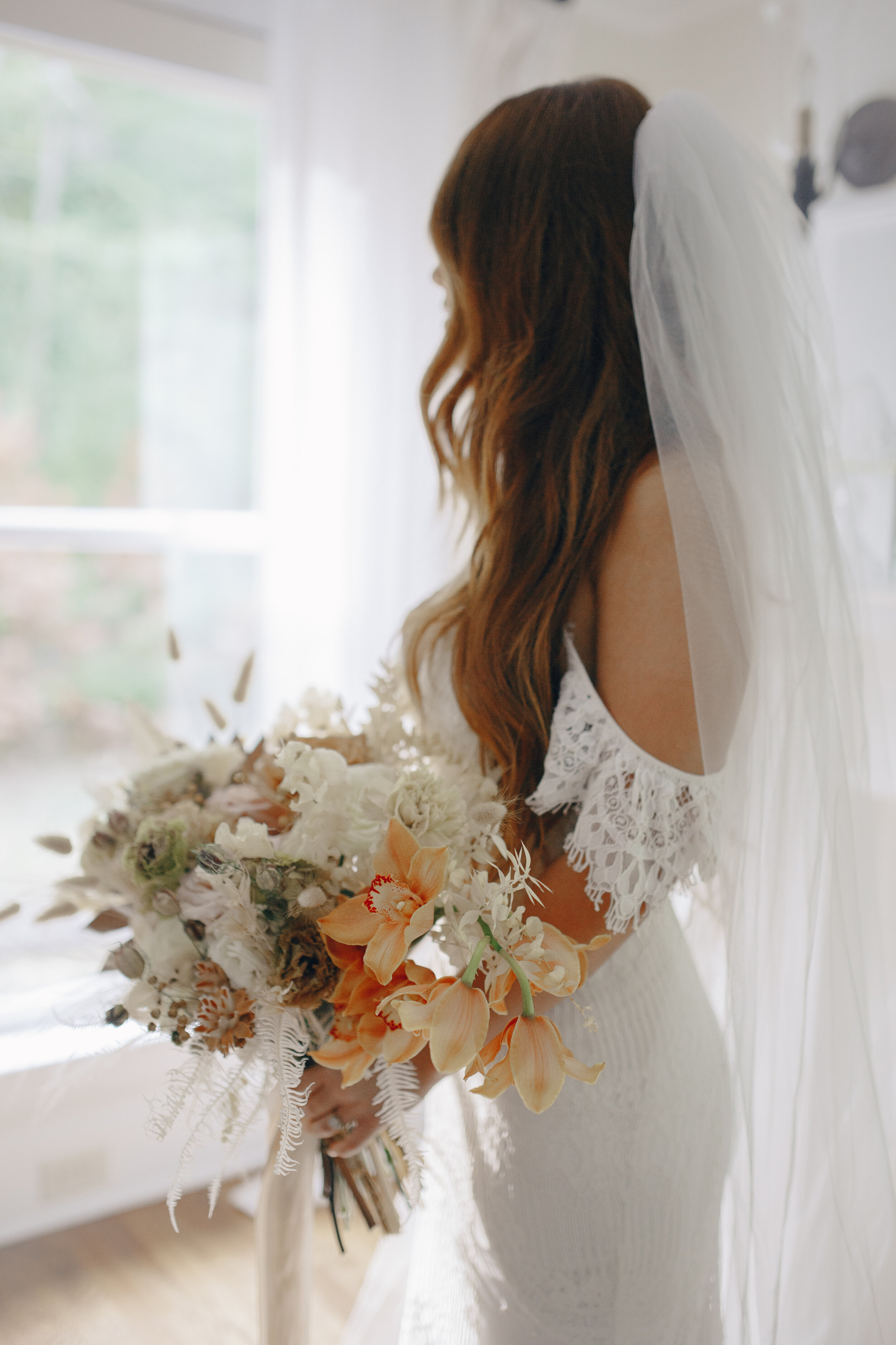 Lush, bohemian bridal bouquet with white garden roses, copper orchids, dried white ferns, earthy textures, and toffee lisianthus. Nashville wedding and elopement floral designer.