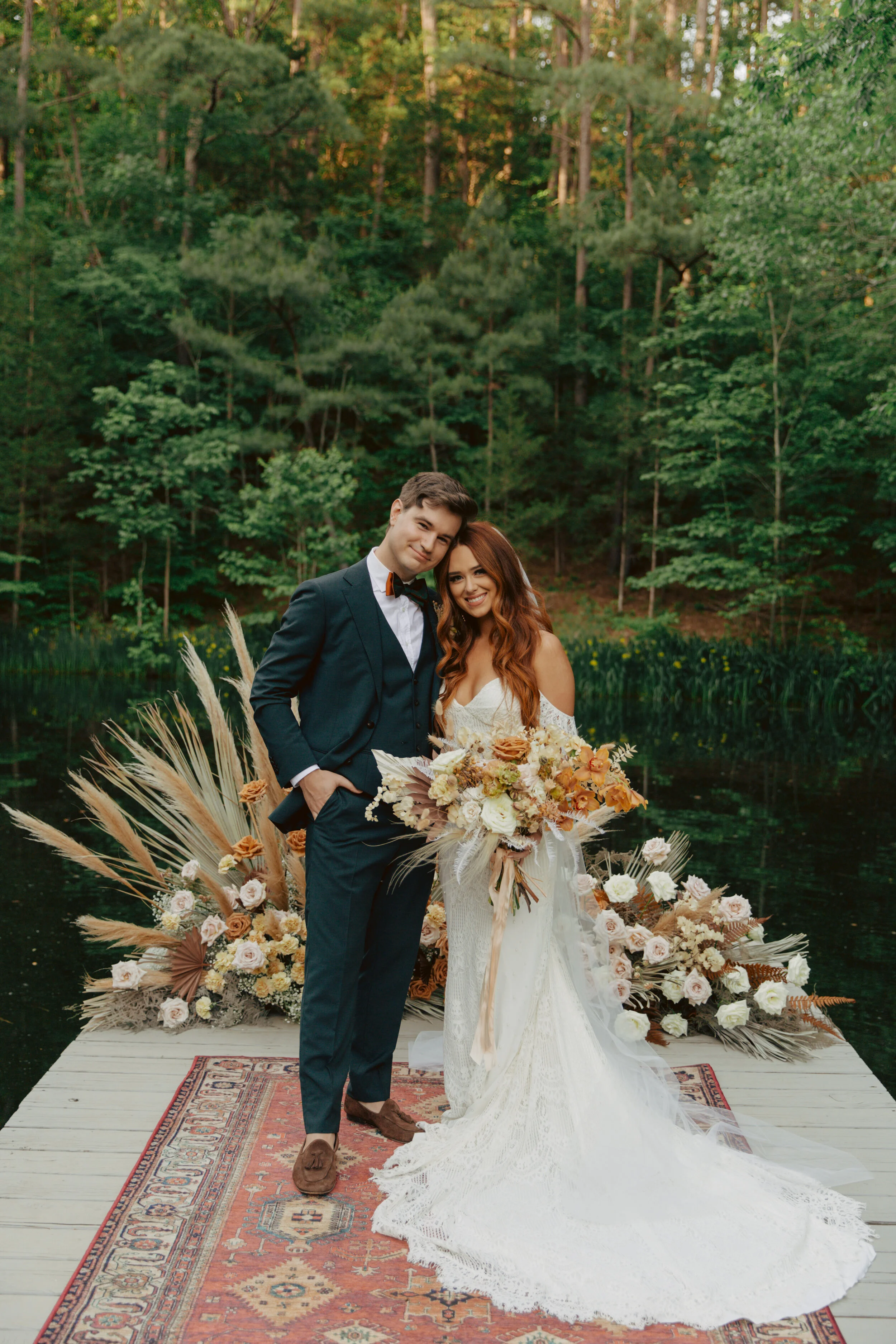 Bohemian, modern floral installation with gold and blush roses, pampas grass, dried ferns, and dried palms, growing on a private dock with a Turkish rug. Nashville wedding florist.