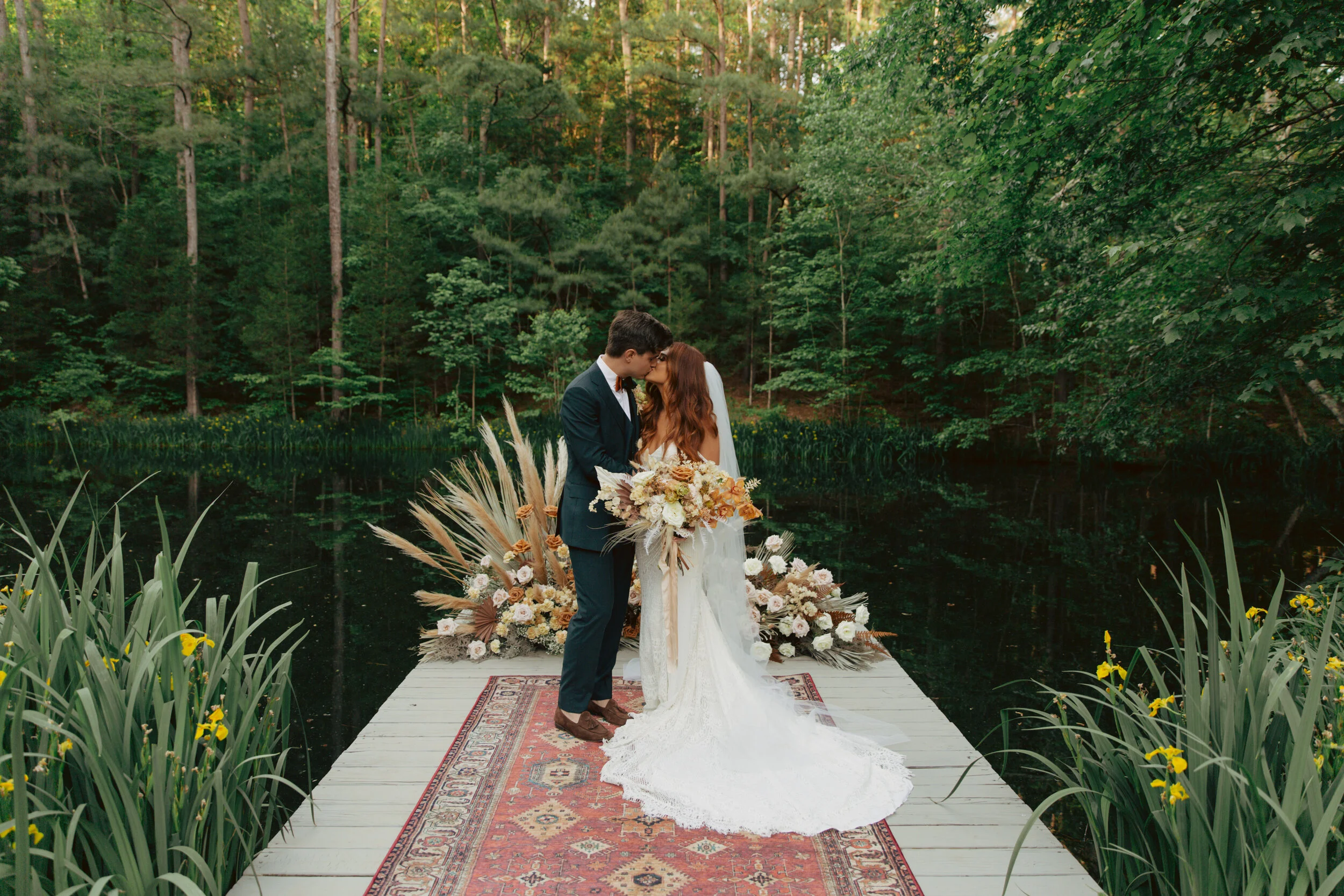 Bohemian, modern floral installation with gold and blush roses, pampas grass, dried ferns, and dried palms, growing on a private dock with a Turkish rug. Nashville wedding florist.