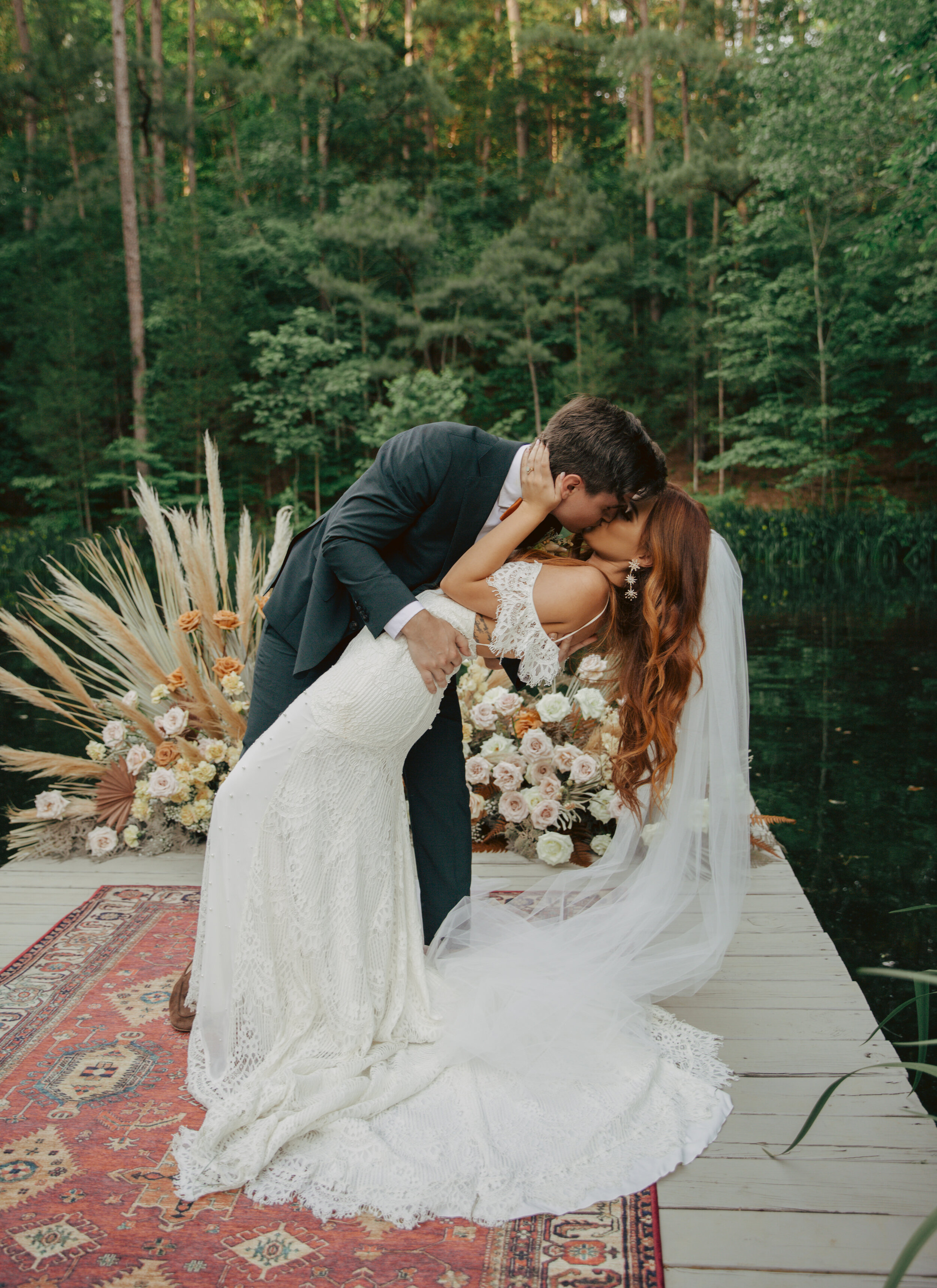 Bohemian, modern floral installation with gold and blush roses, pampas grass, dried ferns, and dried palms, growing on a private dock with a Turkish rug. Nashville wedding florist.