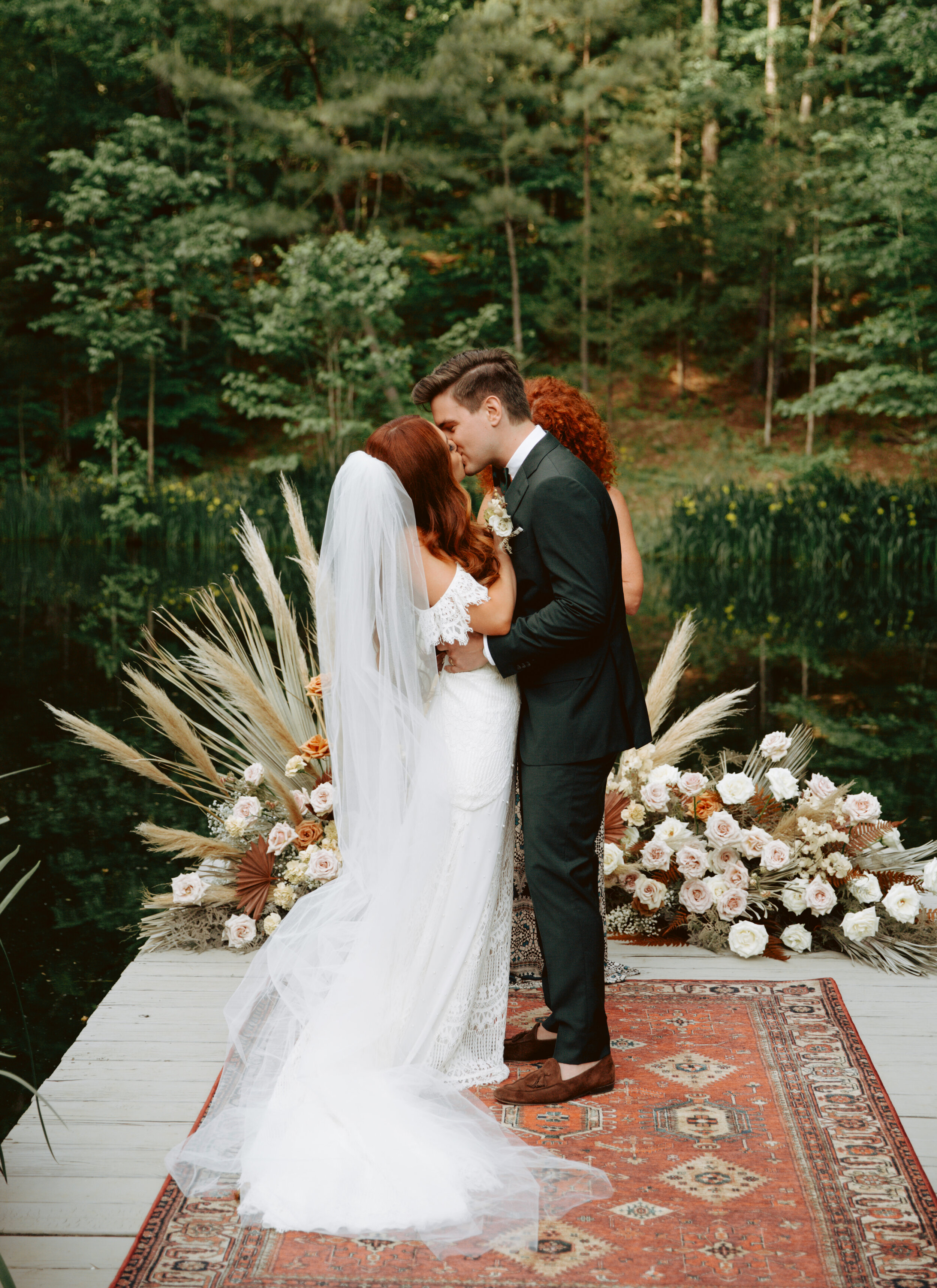 Bohemian, modern floral installation with gold and blush roses, pampas grass, dried ferns, and dried palms, growing on a private dock with a Turkish rug. Nashville wedding florist.