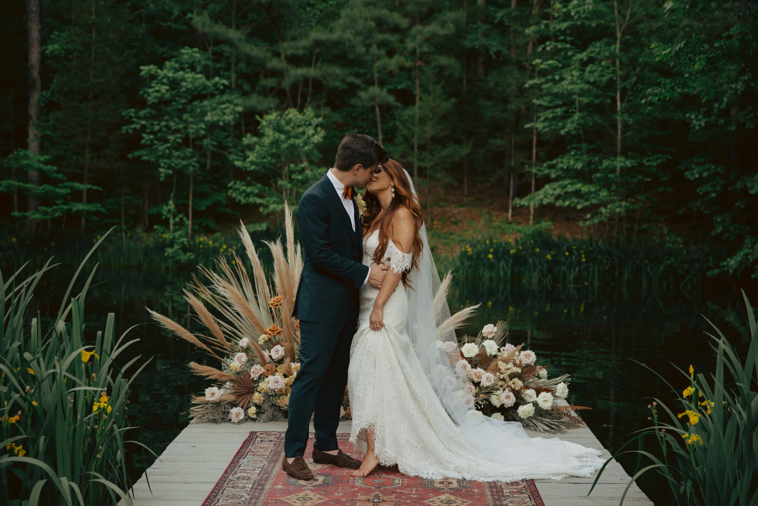 Bohemian, modern floral installation with gold and blush roses, pampas grass, dried ferns, and dried palms, growing on a private dock with a Turkish rug. Nashville wedding florist.
