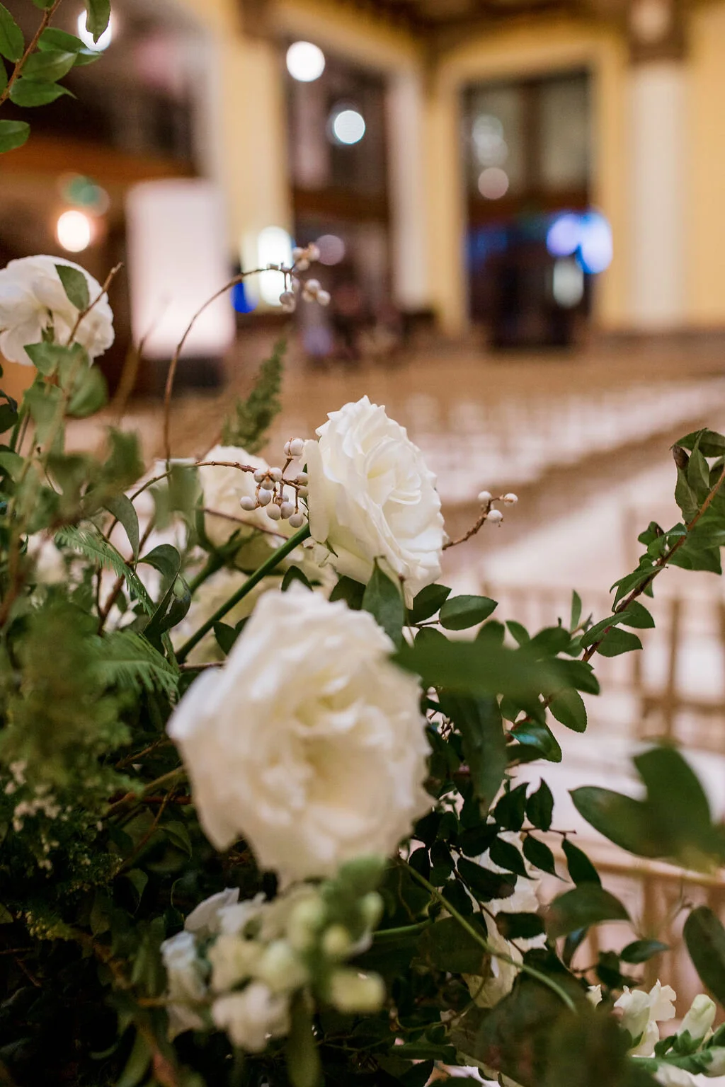 Elevated gold stands with lush floral centerpieces of white garden roses, ranunculus, snapdragons, and natural, untamed greenery. Nashville wedding florist at Union Station.
