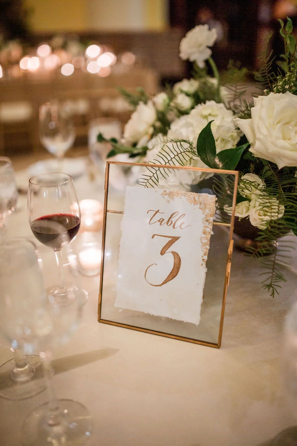 Low floral centerpiece in a gold compote overflowing with white garden roses, hydrangeas, lisianthus, snapdragons, ranunculus, and natural dark greenery. Elegant winter wedding floral design at Union Station, Nashville.