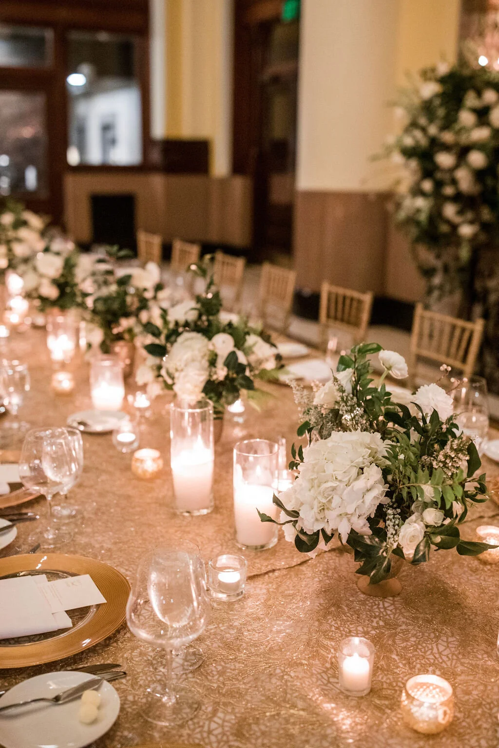 Low floral centerpiece in a gold compote overflowing with white garden roses, hydrangeas, lisianthus, snapdragons, ranunculus, and natural dark greenery. Elegant winter wedding floral design at Union Station, Nashville.