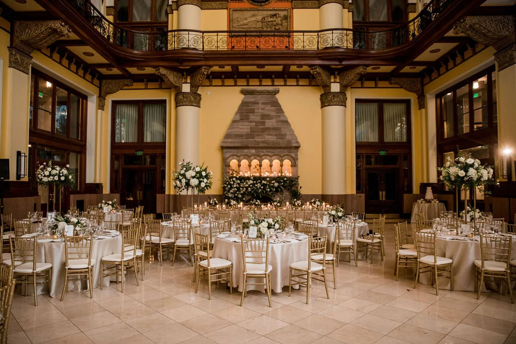 Elevated gold stands with lush floral centerpieces of white garden roses, ranunculus, snapdragons, and natural, untamed greenery. Nashville wedding florist at Union Station.