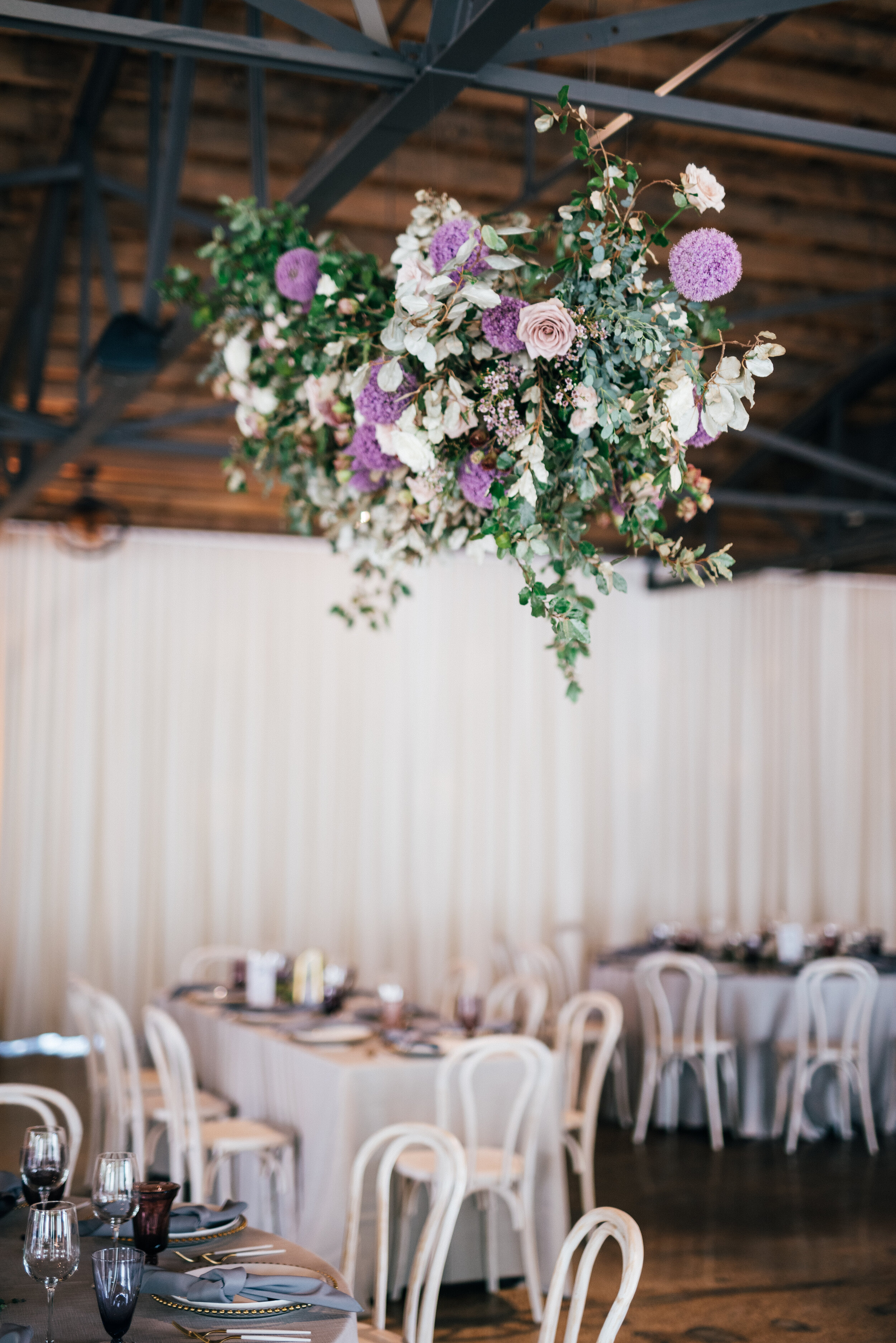 Floating floral cloud installation with mauve garden roses, purple allium, blush spray roses, and lush, untamed greenery. Nashville wedding florist at the Saint Elle.