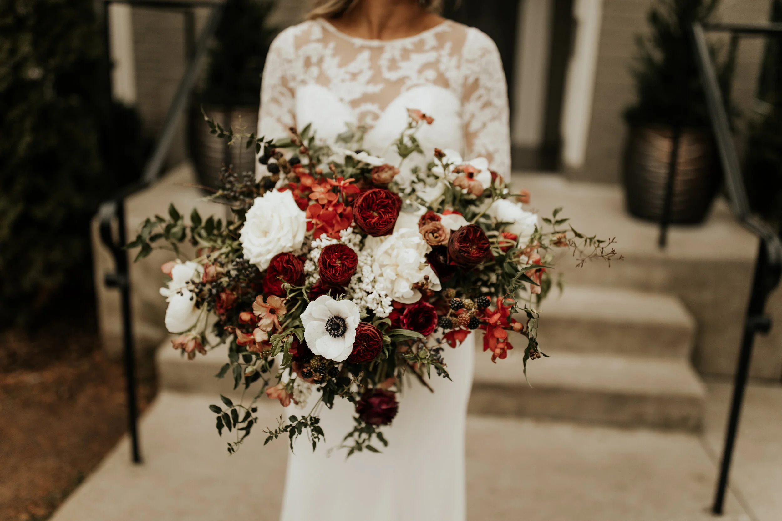 Lush, wintry bridal bouquet with anemones, white and burgundy peonies, ranunculus, garden roses, jasmine vine, and natural greenery. Nashville wedding floral designer, Rosemary & Finch.