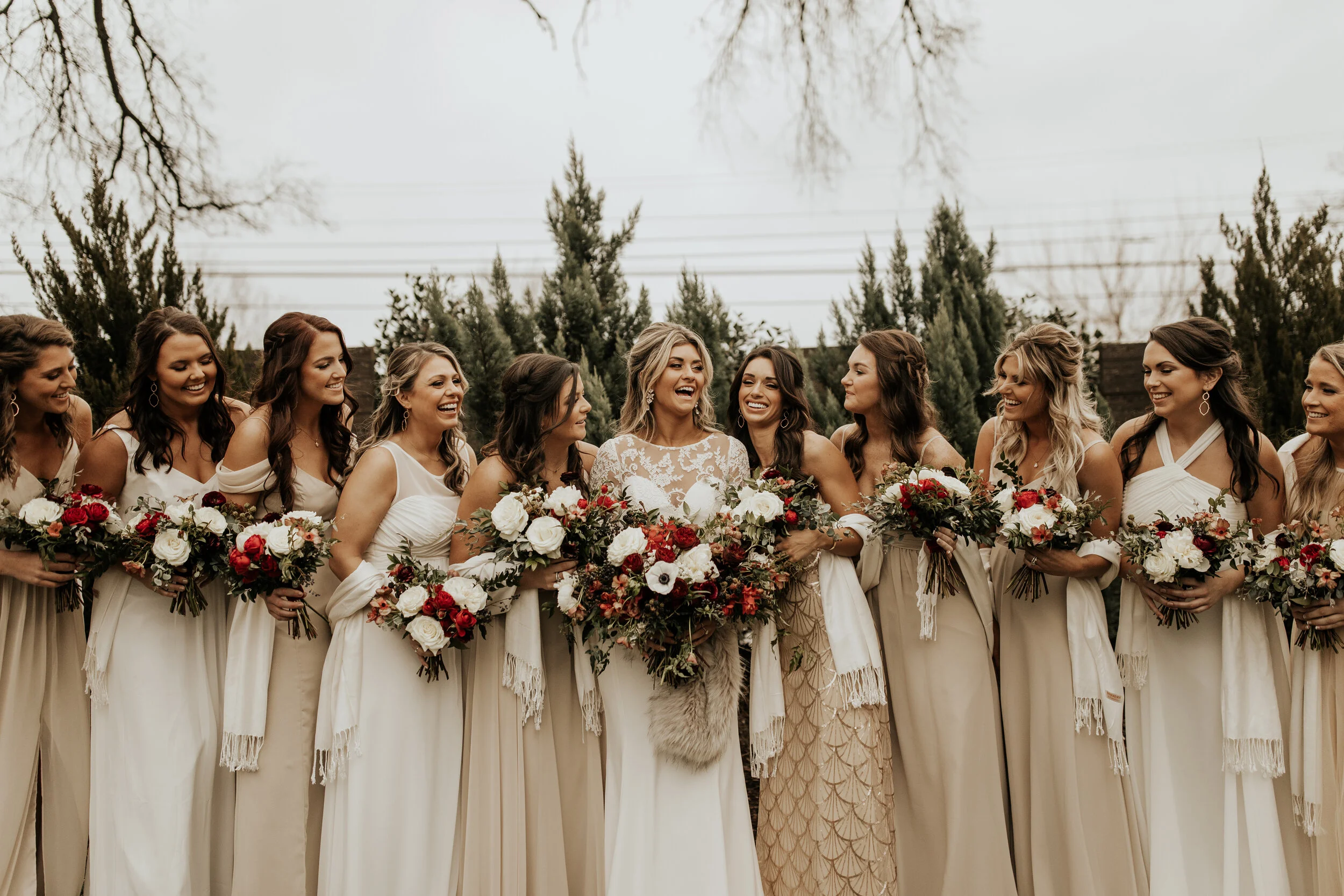 Neutral bridesmaid dresses with burgundy, white, and greenery bouquets of garden roses, peonies, and ranunculus for a wintry wedding at the Cordelle in Nashville.