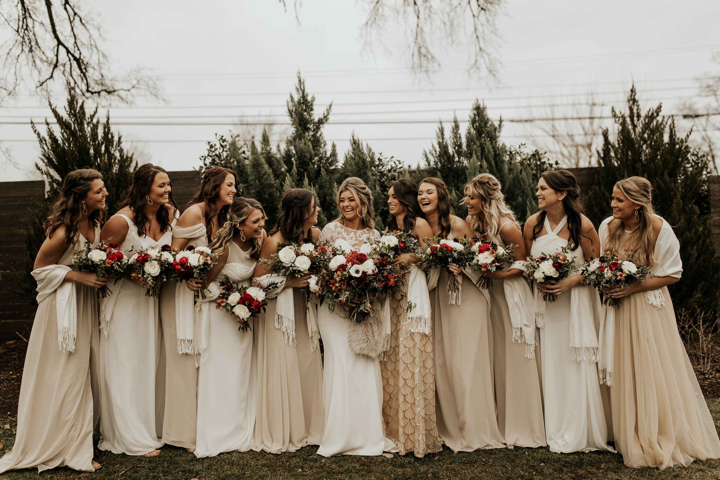 Neutral bridesmaid dresses with burgundy, white, and greenery bouquets of garden roses, peonies, and ranunculus for a wintry wedding at the Cordelle in Nashville.