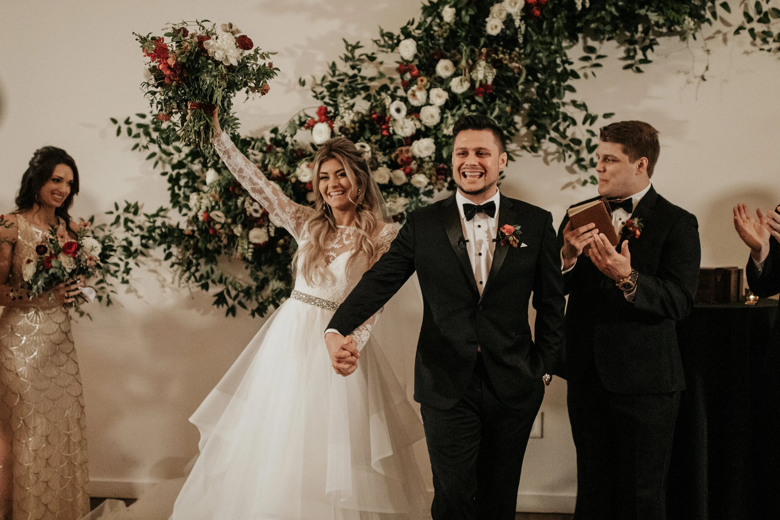 Asymmetrical floral installation growing up the white wall of the Cordelle with natural, untamed greenery, burgundy and white garden roses and ranunculus, and organic textures. Nashville wedding florist.