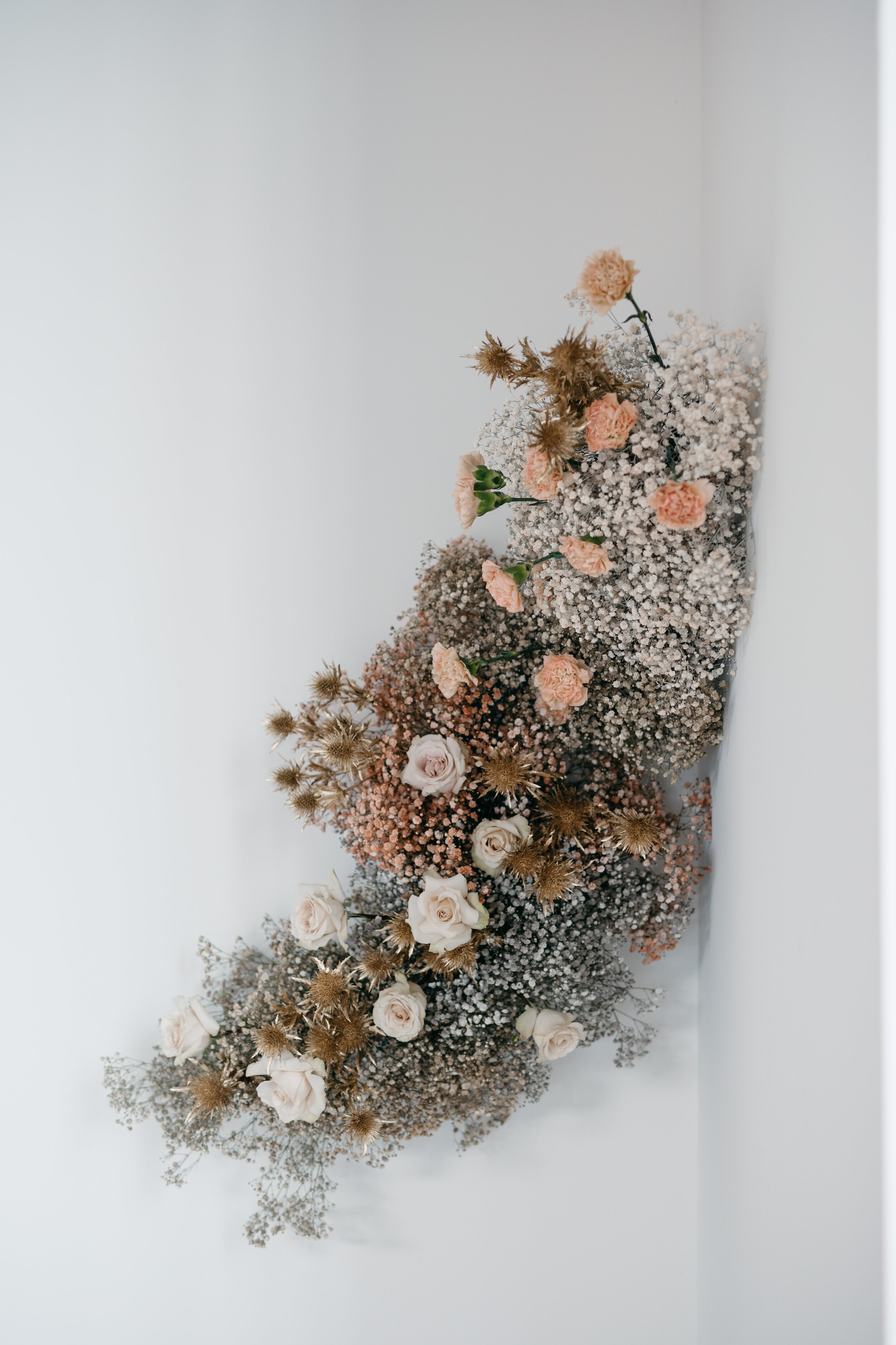 Growing wall installation of fresh and dried florals featuring dyed baby's breath, earth tone carnations, and blush roses. Nashville wedding florist Rosemary & Finch at OZARI.