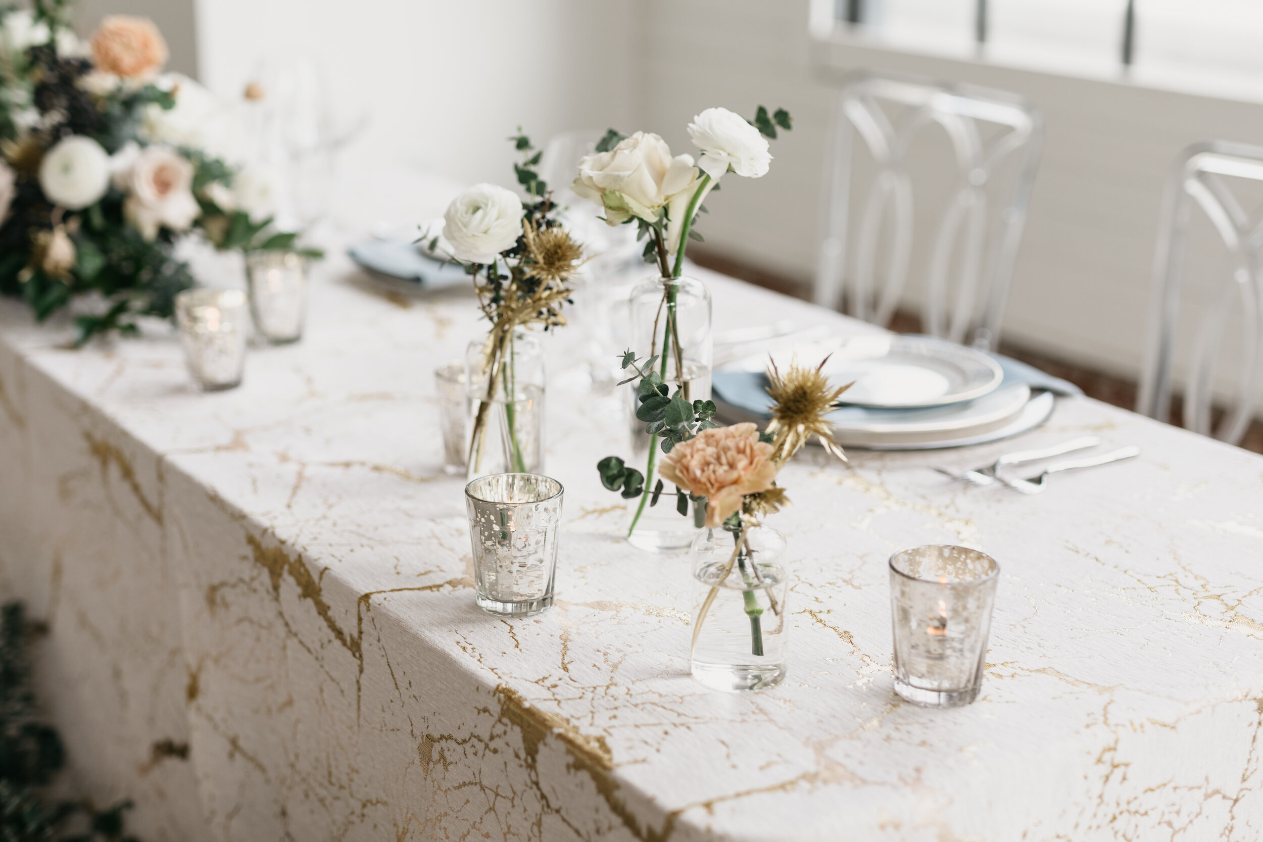 Winter inspiration tablescape featuring sweet bud vases of white roses, touches of gold, baby eucalyptus, and earth tone carnations. Nashville wedding florist Rosemary & Finch at OZARI.