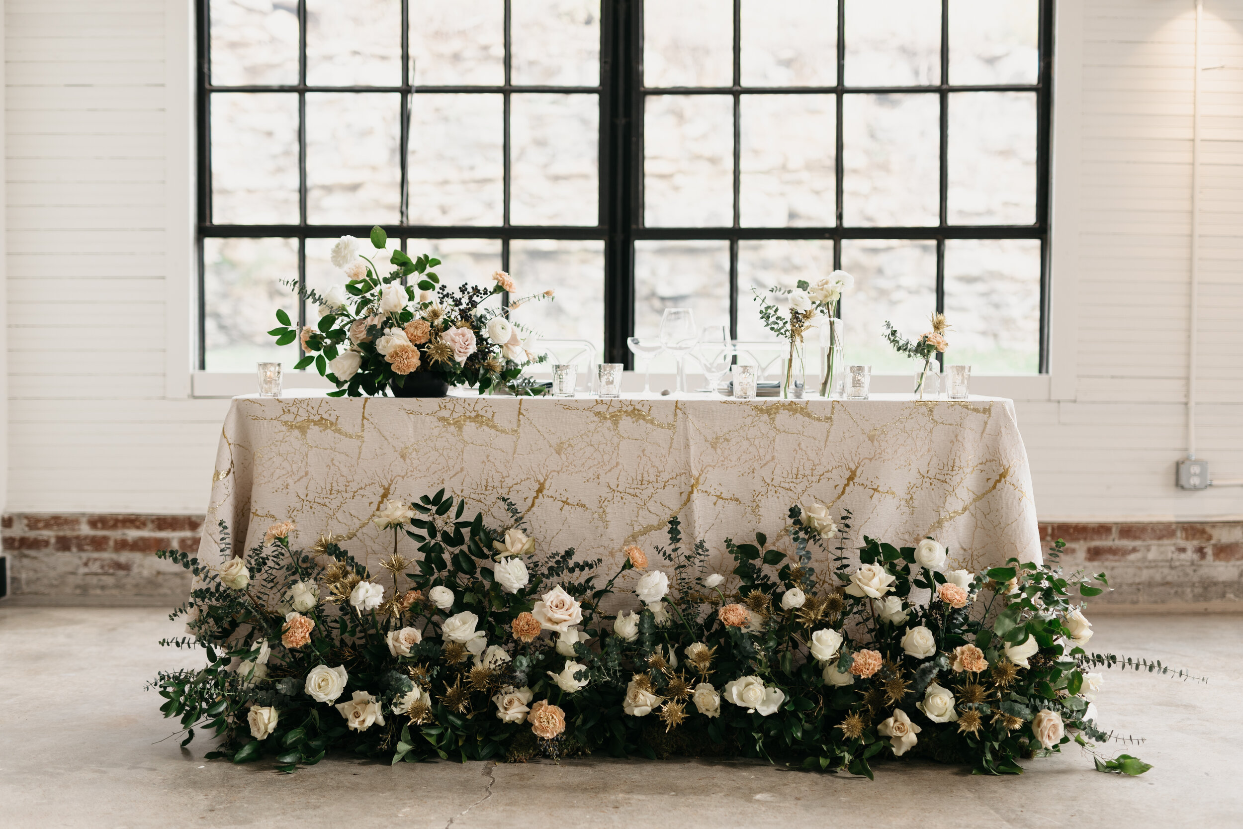 Wintery growing floor installation and tablescape featuring white roses, touches of gold, baby eucalyptus and lush greenery. Nashville wedding florist Rosemary & Finch at OZARI.