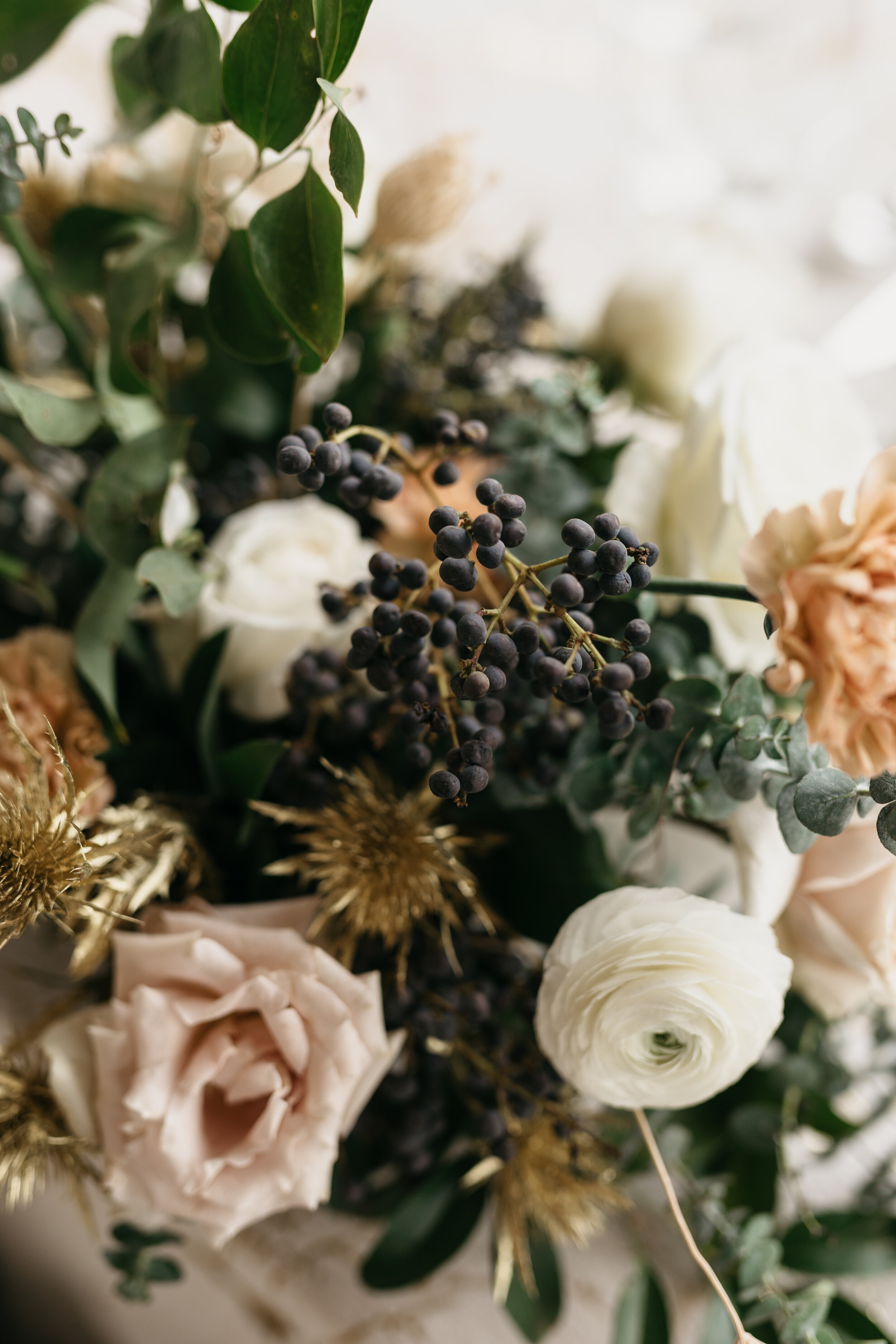 Winter inspiration centerpiece featuring white roses, berries, touches of gold, baby eucalyptus, and lush greenery. Nashville wedding florist Rosemary & Finch at OZARI.