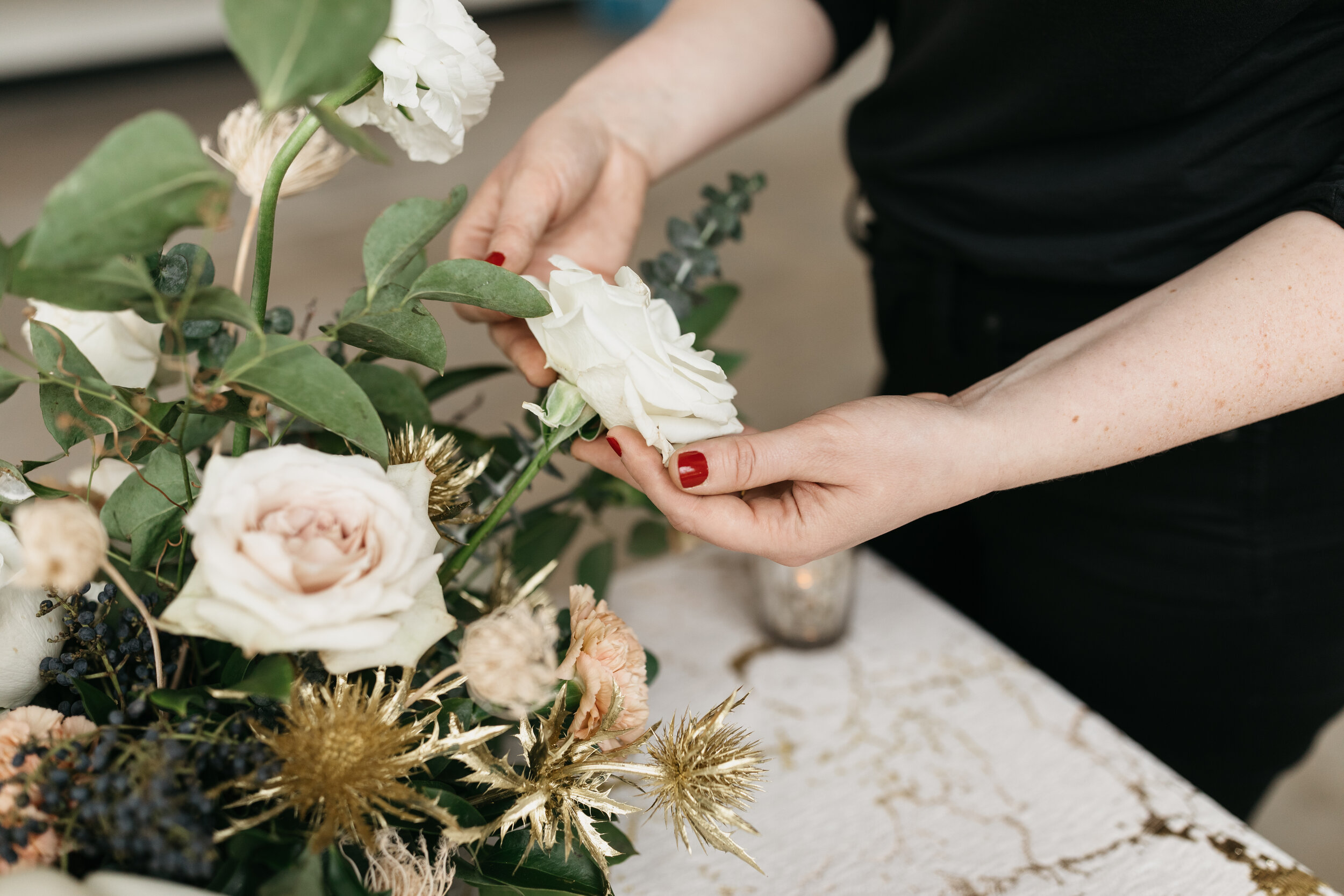 Winter inspiration centerpiece featuring white roses, berries, touches of gold, baby eucalyptus, and lush greenery. Nashville wedding florist Rosemary & Finch at OZARI.