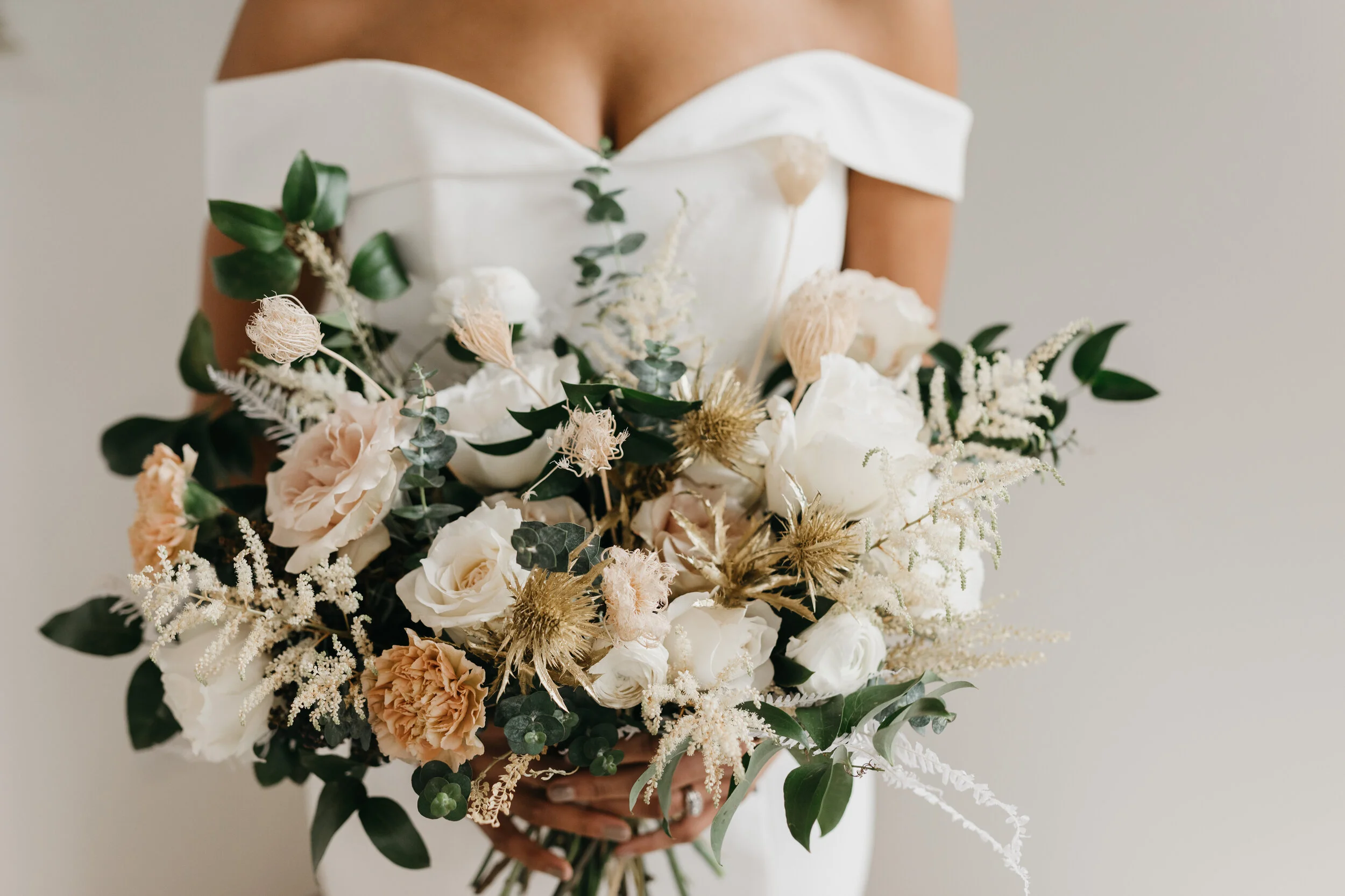 Wintery bouquet filled with fresh and dried florals, white roses, quicksand roses, astilbe, baby eucalyptus, lush greenery, and touches of gold. Nashville wedding florist Rosemary & Finch at OZARI.