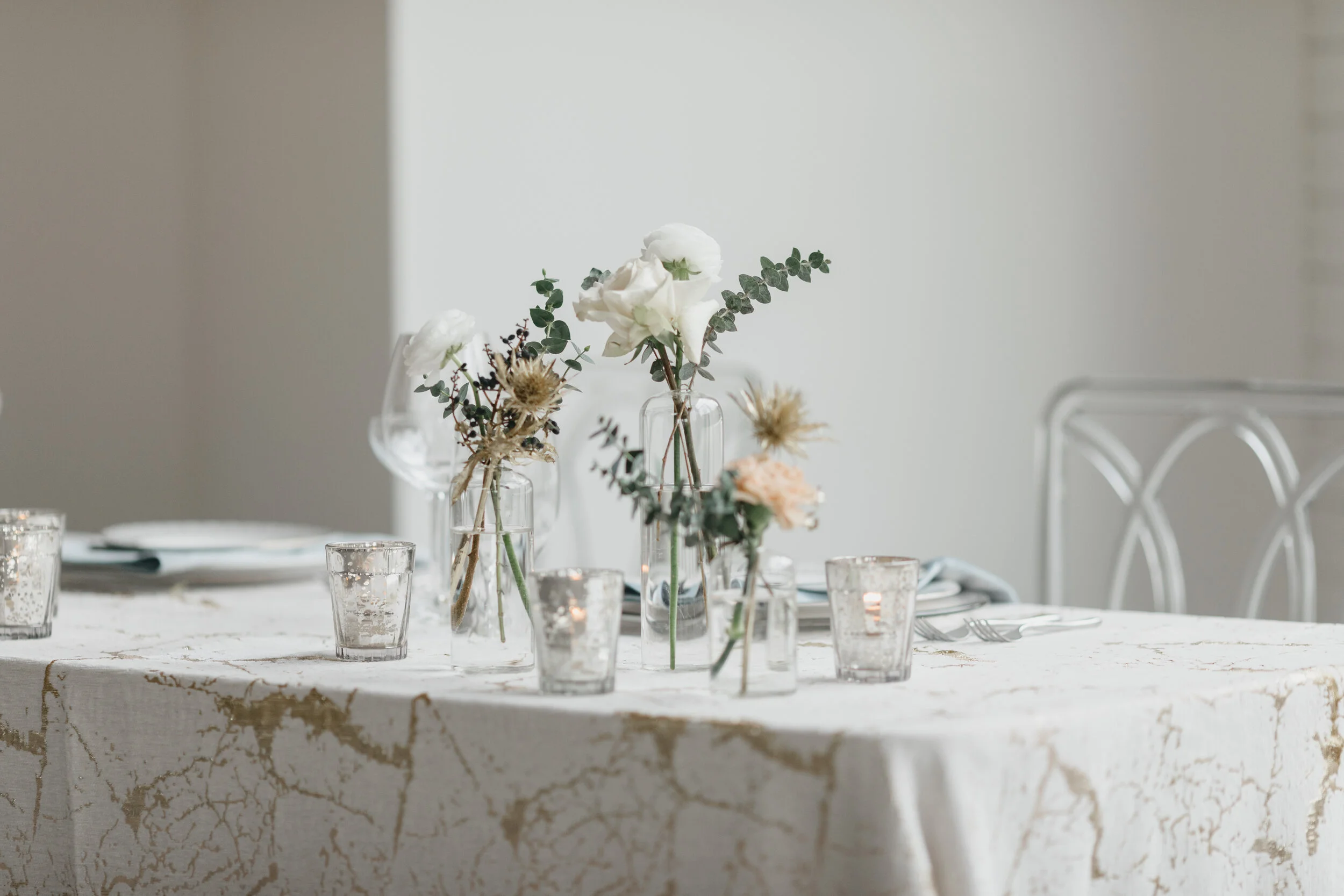 Winter inspiration tablescape featuring sweet bud vases of white roses, touches of gold, baby eucalyptus, and earth tone carnations. Nashville wedding florist Rosemary & Finch at OZARI.