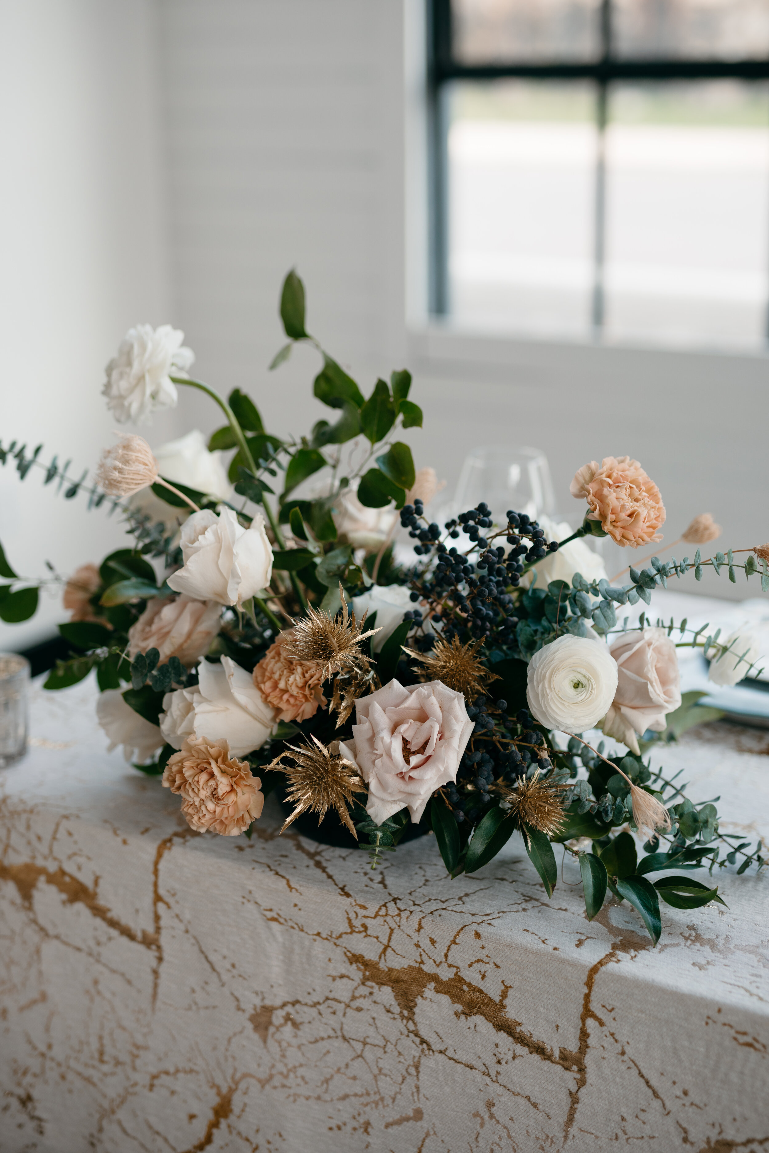 Winter inspiration centerpiece featuring white and blush roses, berries, touches of gold, baby eucalyptus, and lush greenery. Nashville wedding florist Rosemary & Finch at OZARI.