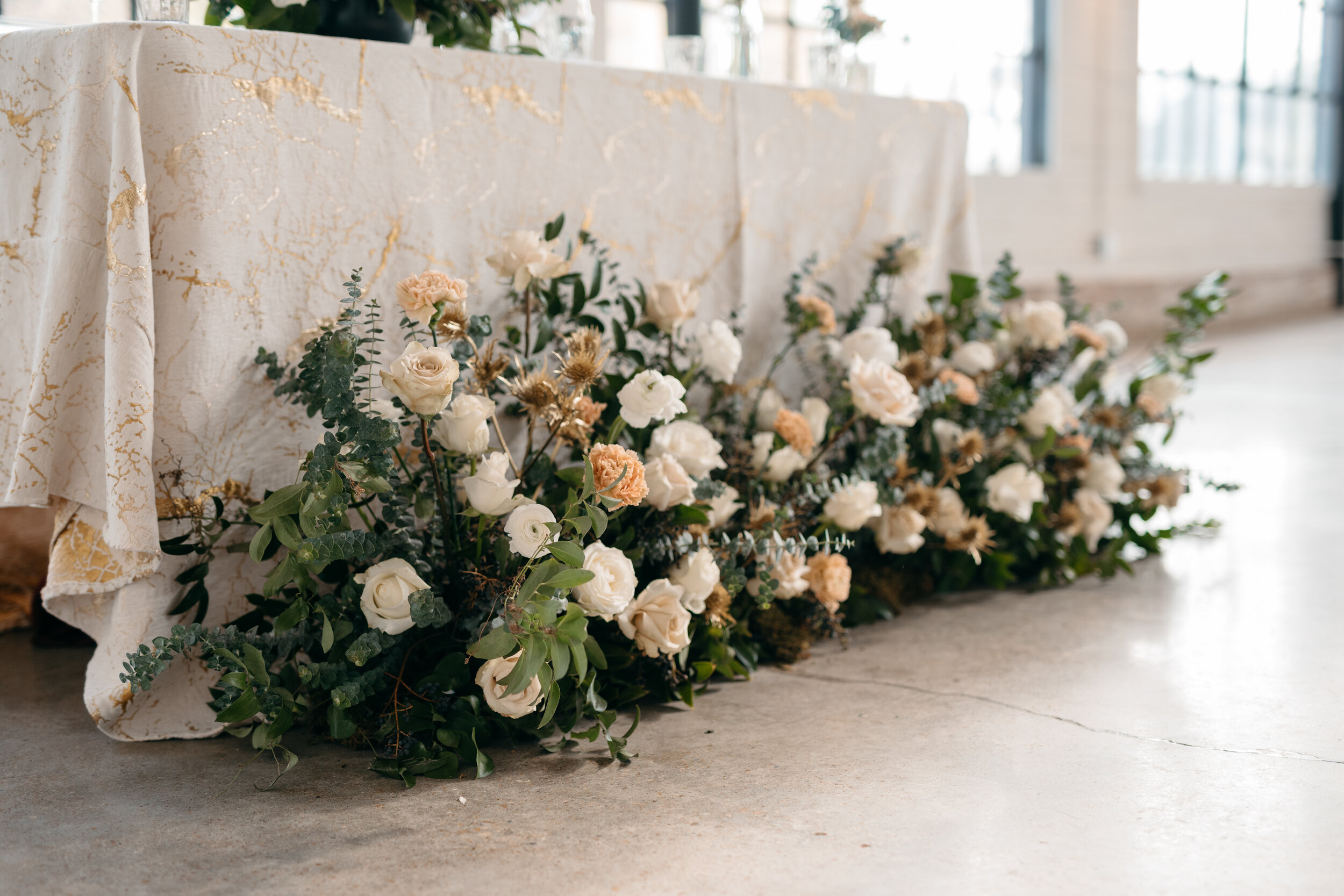 Wintery growing floor installation and tablescape featuring white and quicksand roses, touches of gold, baby eucalyptus and lush greenery. Nashville wedding florist Rosemary & Finch at OZARI.