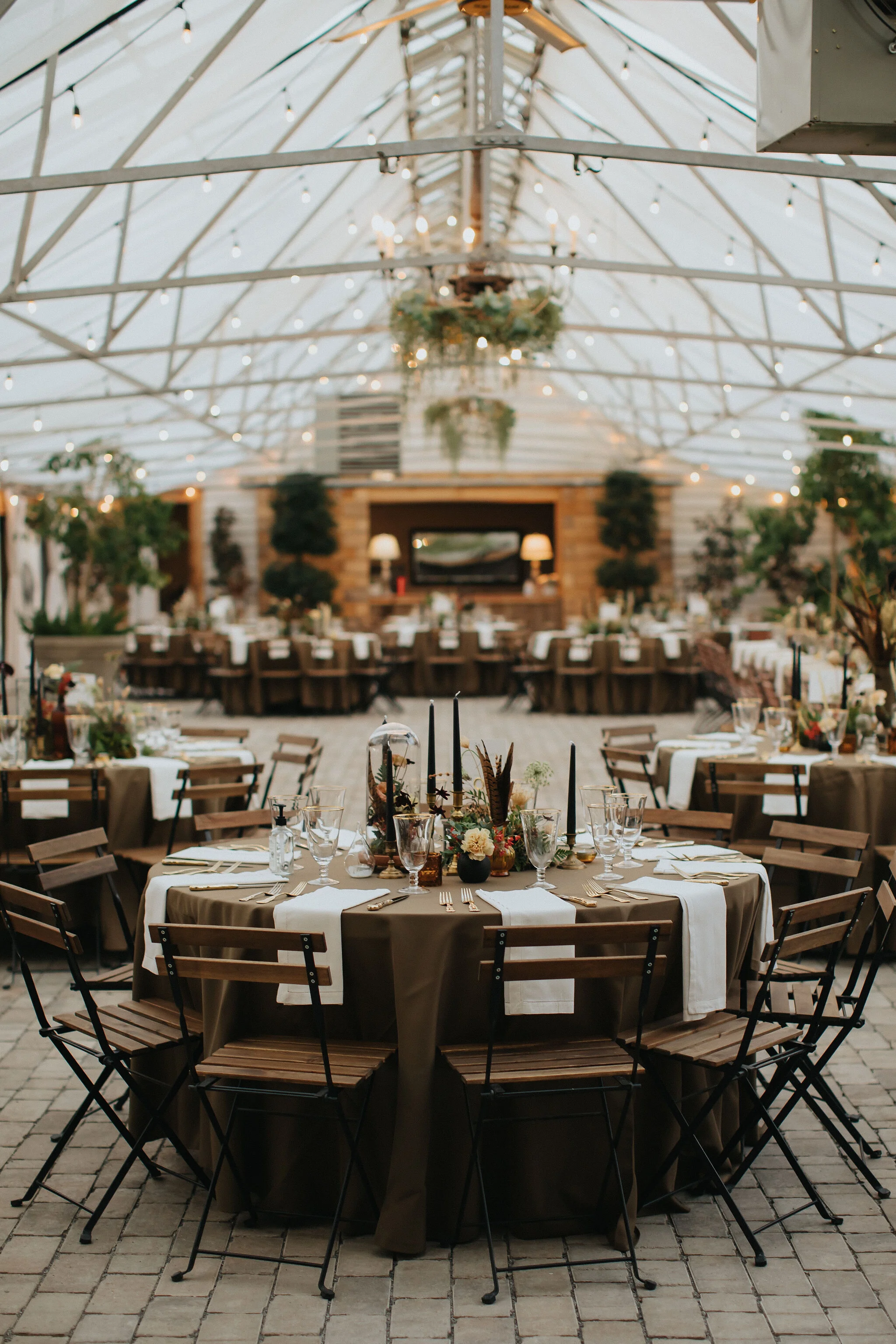 Earthy and romantic – this eclectic tablescape is crafted from pheasant feathers, brass candlesticks, and layered florals. Botanical cloches are filled with fern, moss, chocolate cosmos, and ranunculus. Designed by Nashville wedding floral designer,…