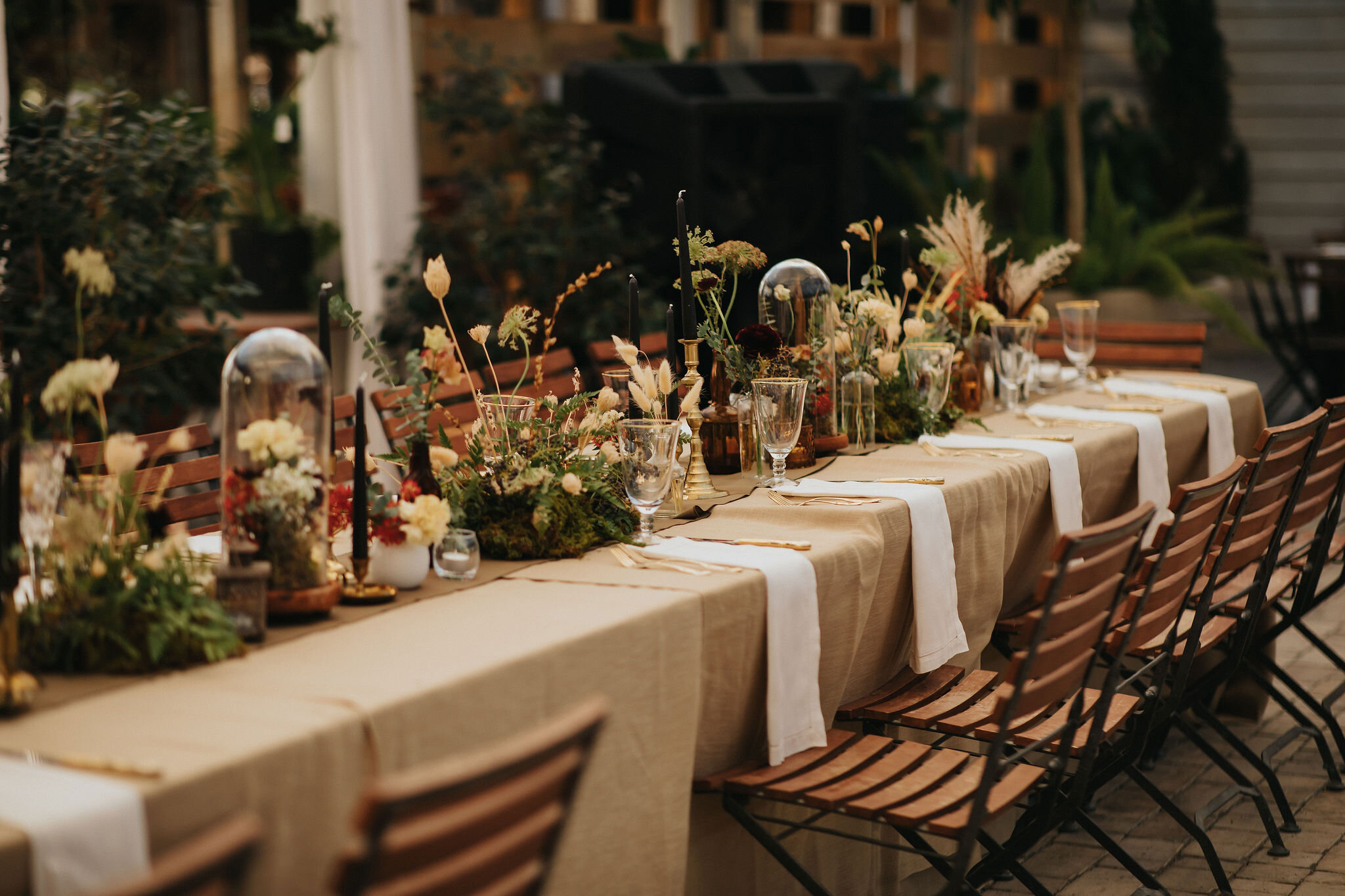 Earthy and romantic – this eclectic tablescape is crafted from pheasant feathers, brass candlesticks, and layered florals. Botanical cloches are filled with fern, moss, chocolate cosmos, and ranunculus. Designed by Nashville wedding floral designer,…