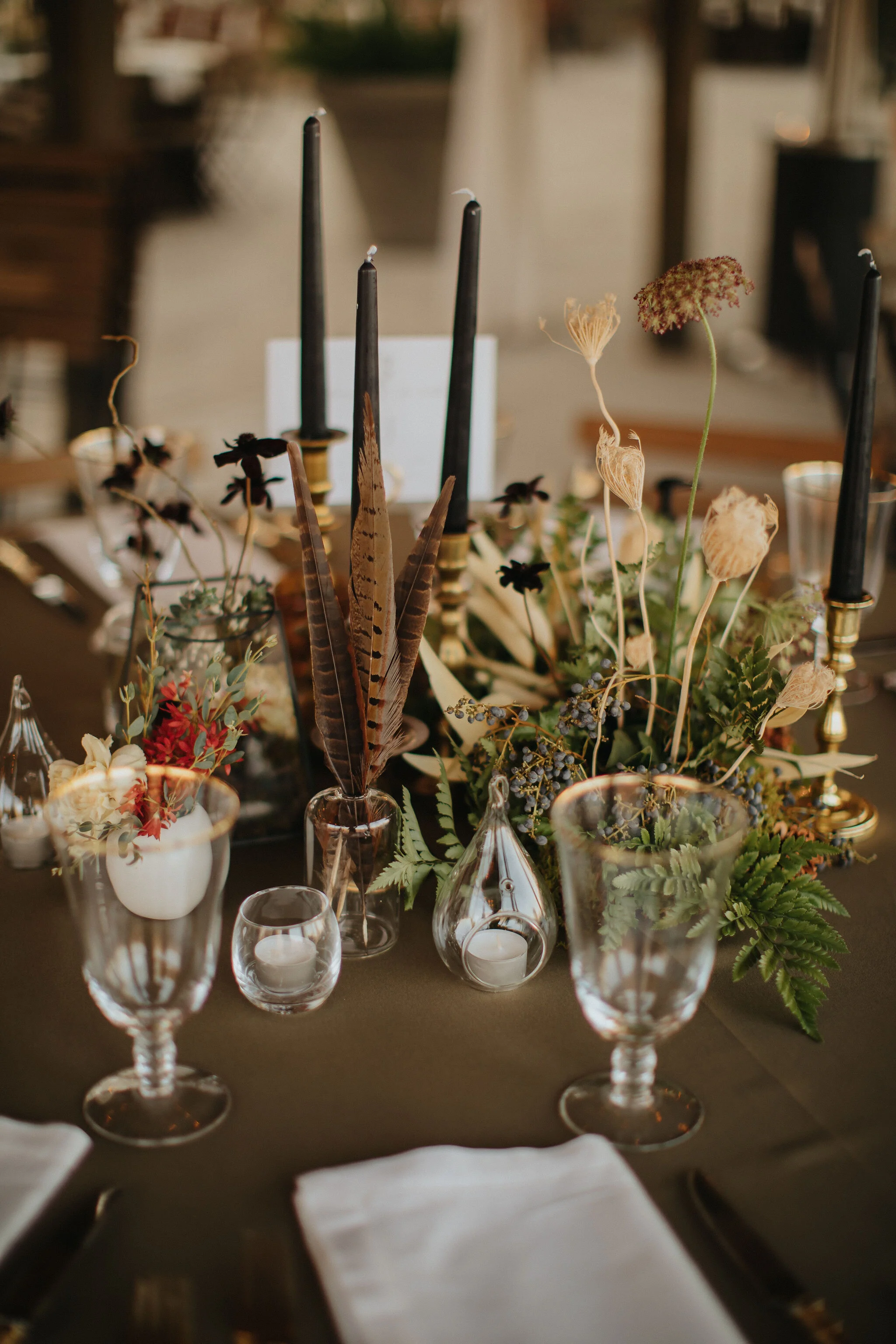 Earthy and romantic – this eclectic tablescape is crafted from pheasant feathers, brass candlesticks, and layered florals. Botanical cloches are filled with fern, moss, chocolate cosmos, and ranunculus. Designed by Nashville wedding floral designer,…