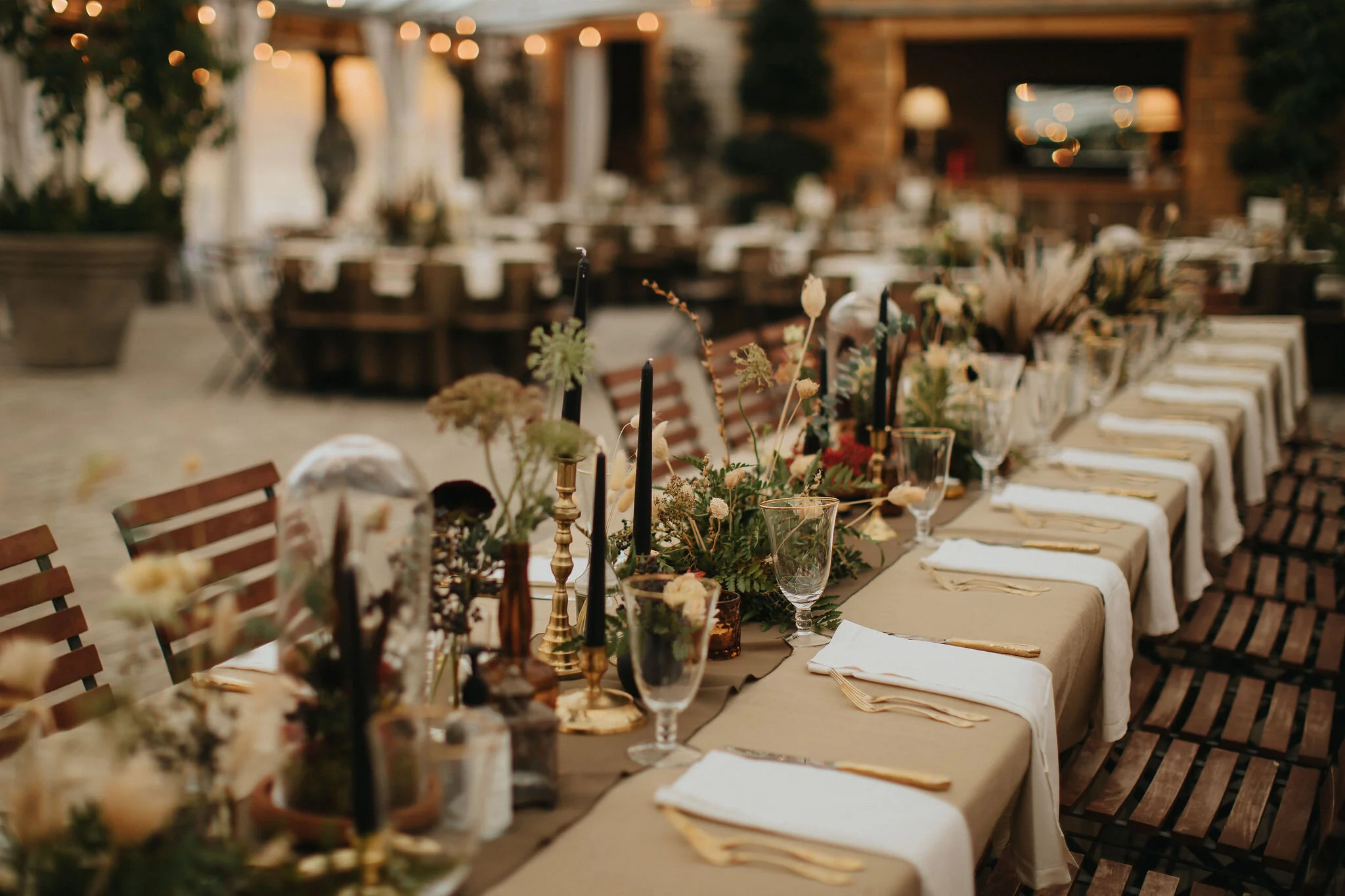 Earthy and romantic – this eclectic tablescape is crafted from pheasant feathers, brass candlesticks, and layered florals. Botanical cloches are filled with fern, moss, chocolate cosmos, and ranunculus. Designed by Nashville wedding floral designer,…