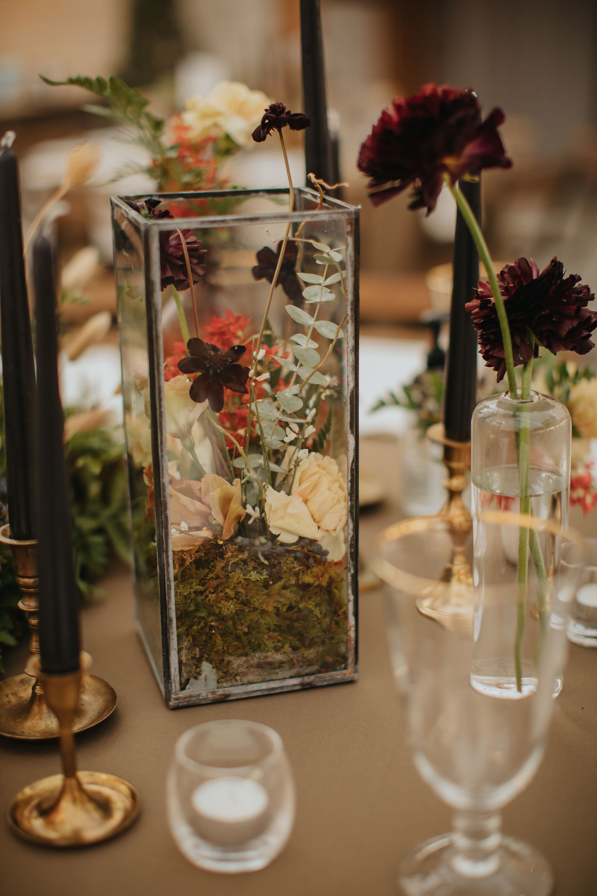 Earthy and romantic – this eclectic tablescape is crafted from pheasant feathers, brass candlesticks, and layered florals. Botanical cloches are filled with fern, moss, chocolate cosmos, and ranunculus. Designed by Nashville wedding floral designer,…