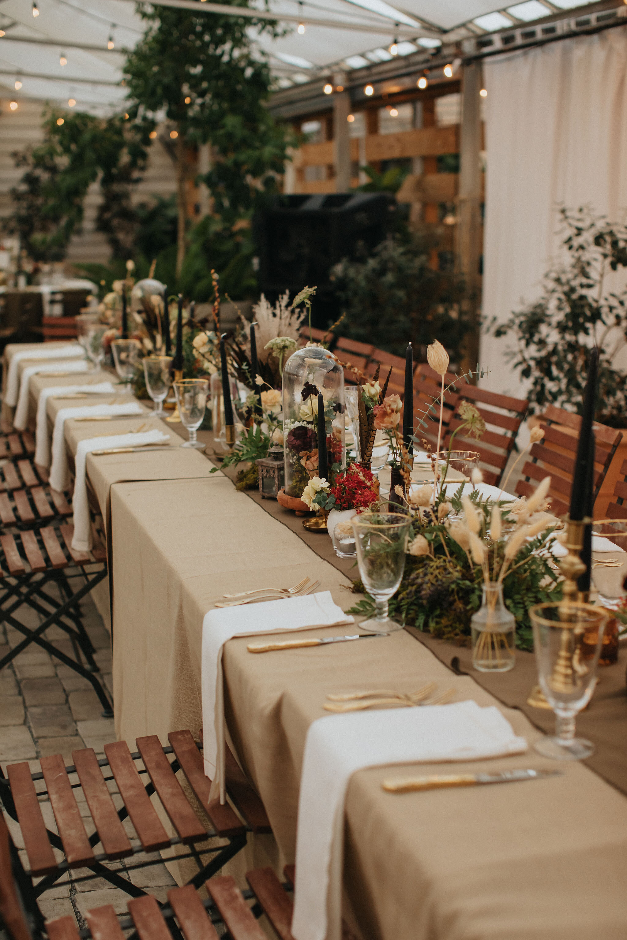 Earthy and romantic – this eclectic tablescape is crafted from pheasant feathers, brass candlesticks, and layered florals. Botanical cloches are filled with fern, moss, chocolate cosmos, and ranunculus. Designed by Nashville wedding floral designer,…