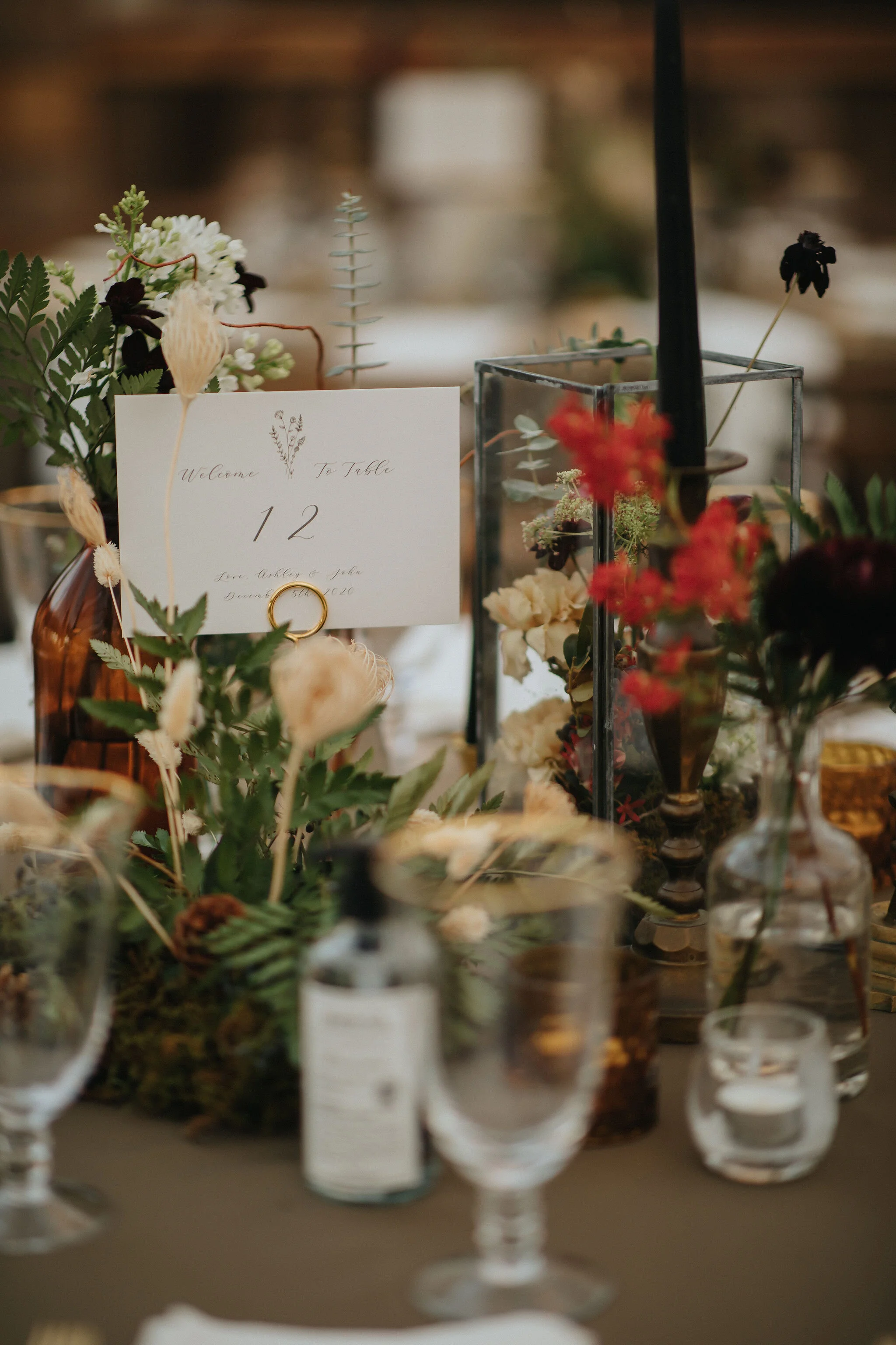 Earthy and romantic – this eclectic tablescape is crafted from pheasant feathers, brass candlesticks, and layered florals. Botanical cloches are filled with fern, moss, chocolate cosmos, and ranunculus. Designed by Nashville wedding floral designer,…