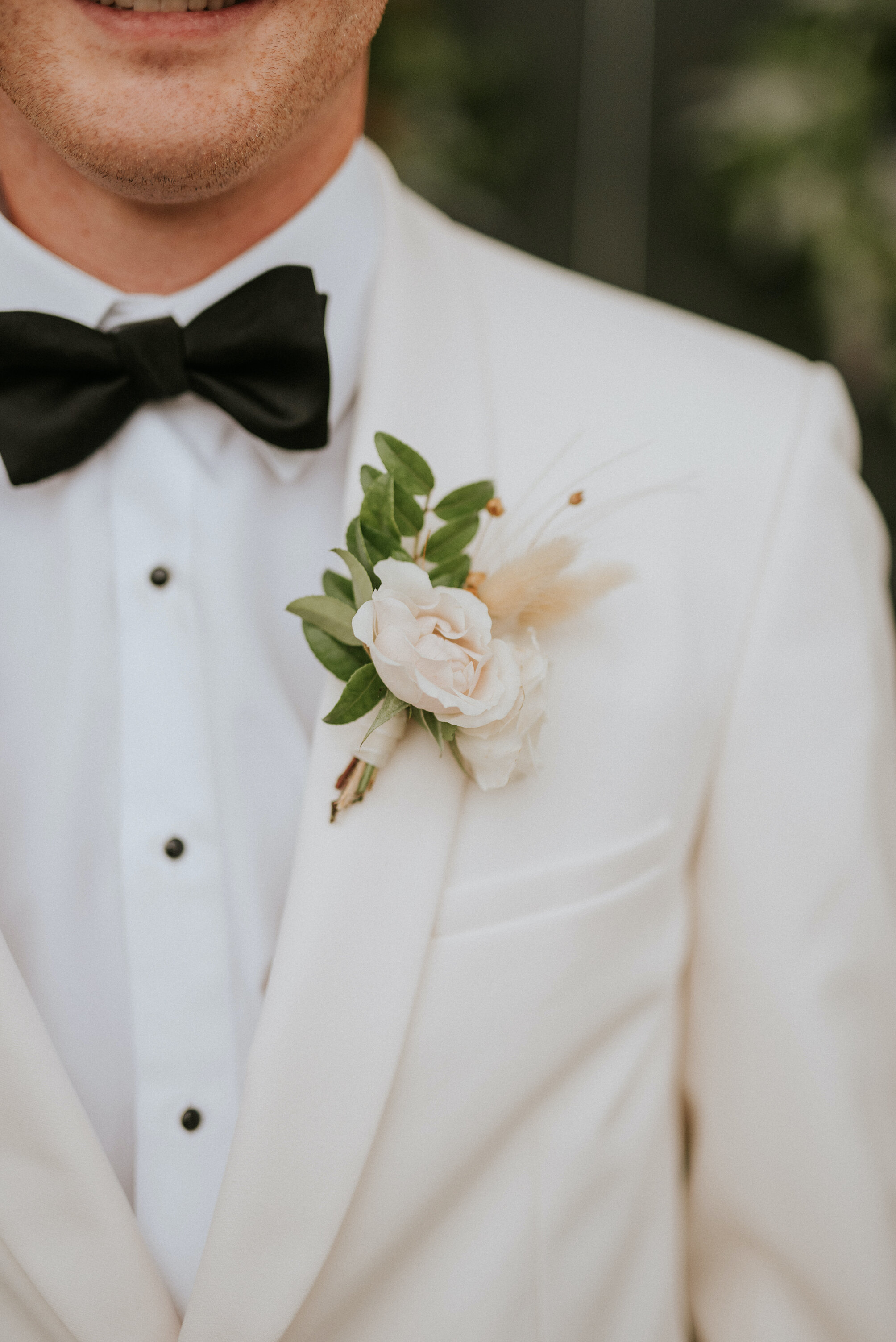 Delicate, boho boutonnière of huckleberry, majolica spray roses, and pampas grass. Designed by Nashville wedding floral designer, Rosemary & Finch at Cheekwood Botanical Gardens