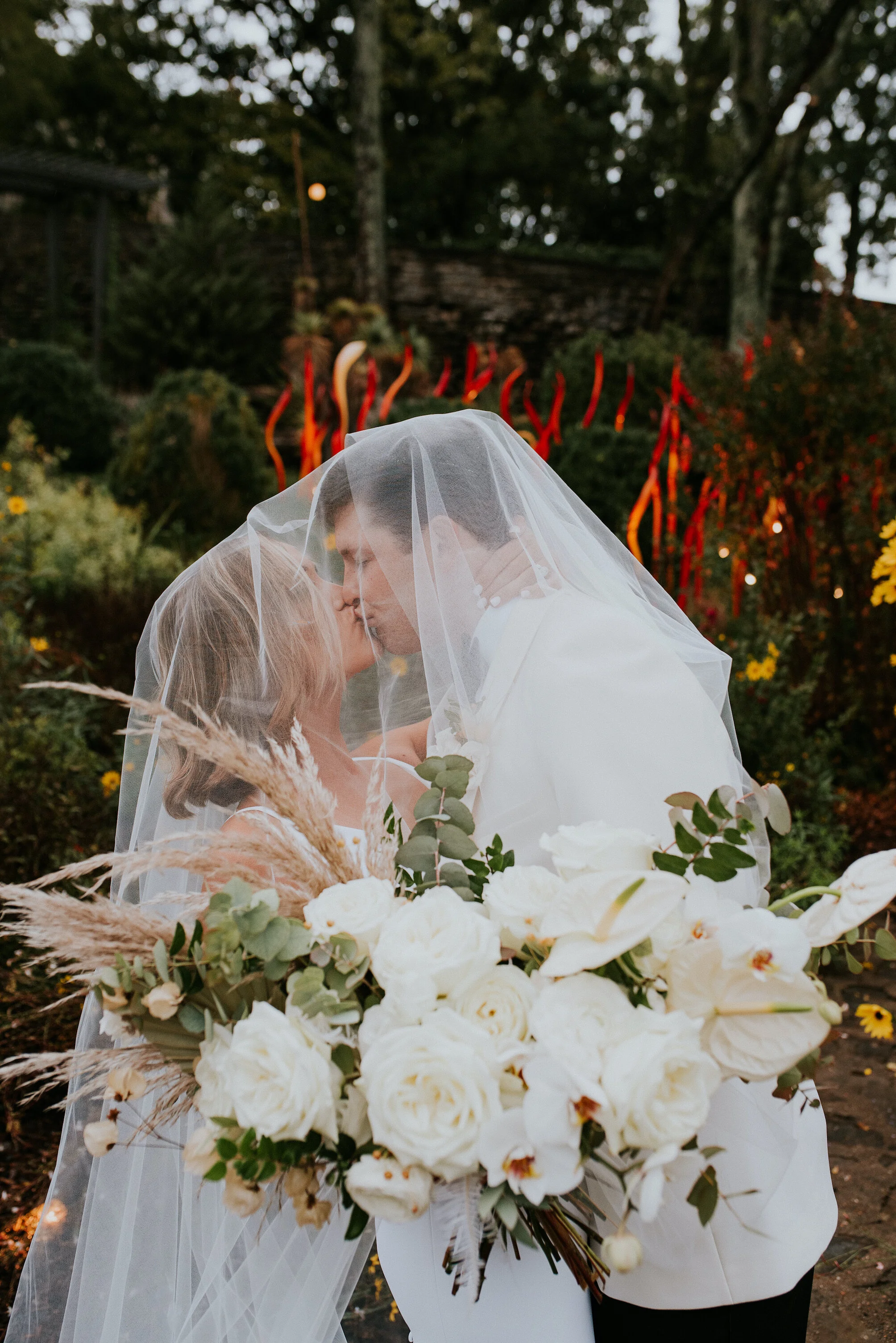 Bohemian and modern yet classically elegant. This Bridal bouquet perfectly married boho elements of pampas grass, eucalyptus, and dried florals with topical stems of anthurium, orchid and ranunculus for a fresh take on white. Designed by Nashville w…