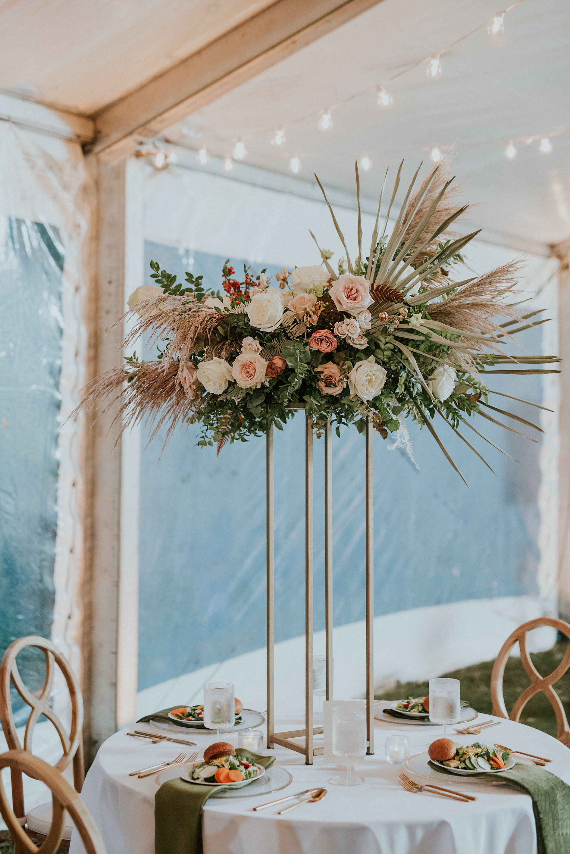 Bohemian and modern yet classically elegant. This wedding perfectly married boho elements of pampas grass, eucalyptus, and dried florals with topical stems of anthurium and orchid. Quicksand roses, cappuccino roses, ilex berry, and rust fern add a p…
