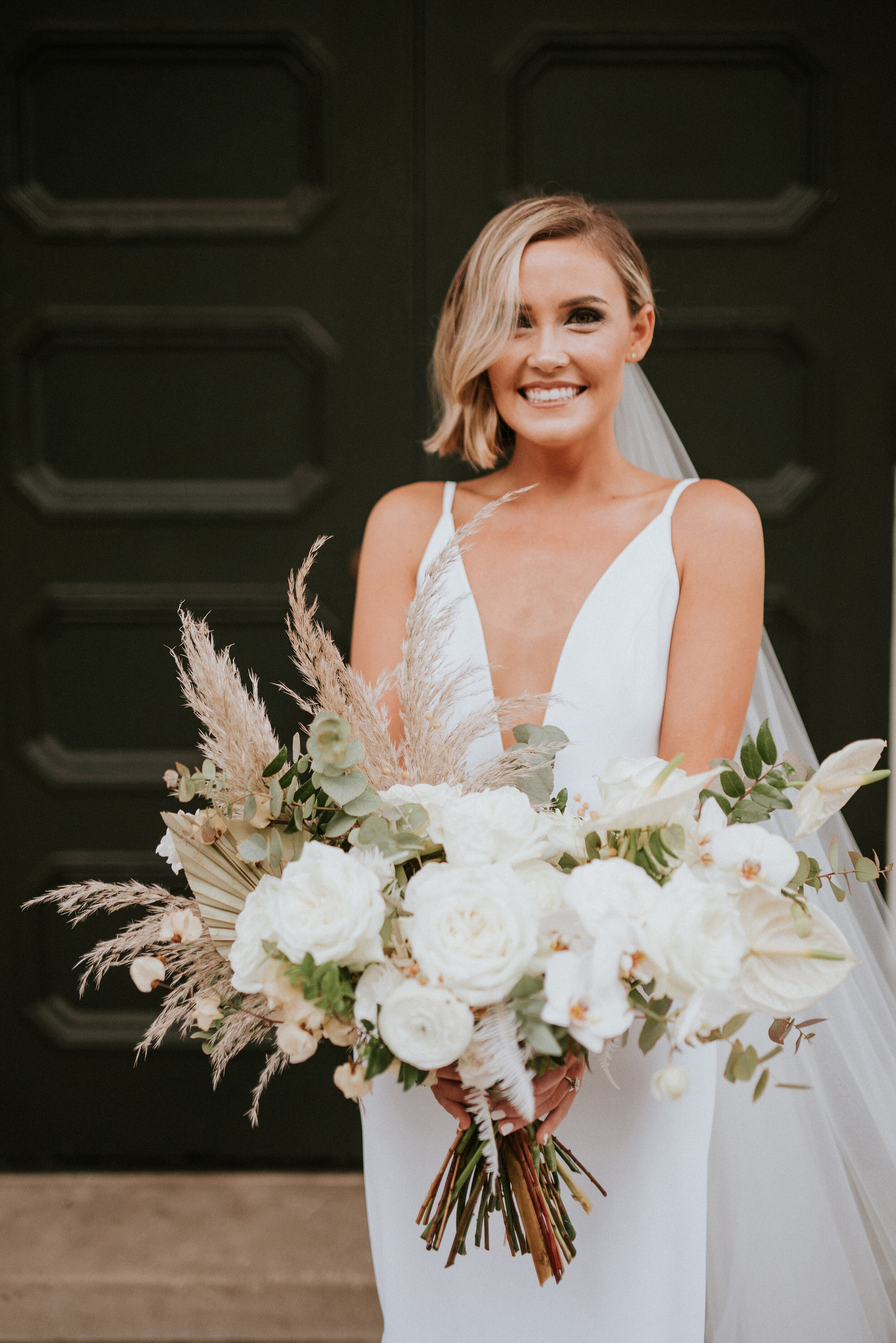 Bohemian and modern yet classically elegant. This Bridal bouquet perfectly married boho elements of pampas grass, eucalyptus, and dried florals with topical stems of anthurium, orchid and ranunculus for a fresh take on white. Designed by Nashville w…