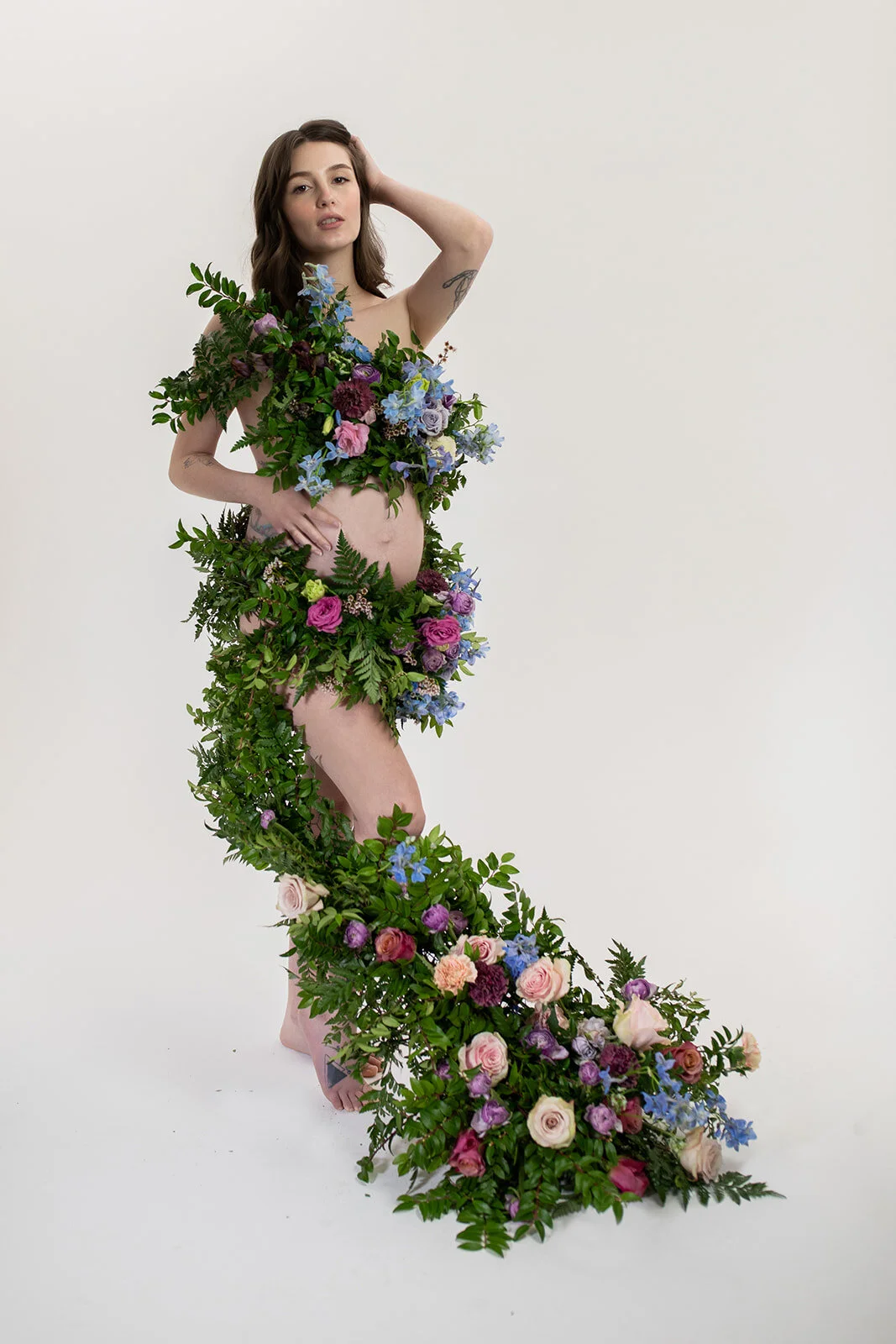 Greek inspired maternity shoot with a wearable floral garland filled with blue delphinium, lavender spray roses, plum ranunculus, blush and fuchsia roses. Designed by wedding florist Rosemary & Finch in Nashville.