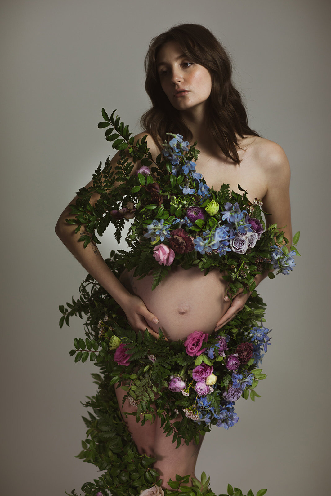 Greek inspired maternity shoot with a wearable floral garland filled with blue delphinium, lavender spray roses, plum ranunculus, blush and fuchsia roses. Designed by wedding florist Rosemary & Finch in Nashville.