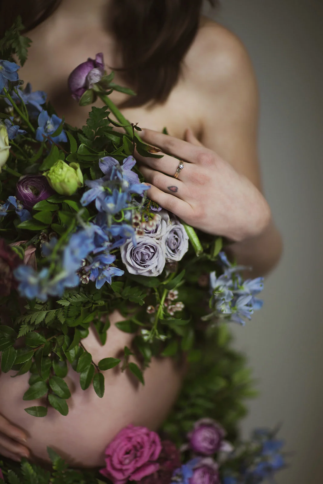 Greek inspired maternity shoot with a wearable floral garland filled with blue delphinium, lavender spray roses, plum ranunculus, blush and fuchsia roses. Designed by wedding florist Rosemary & Finch in Nashville.